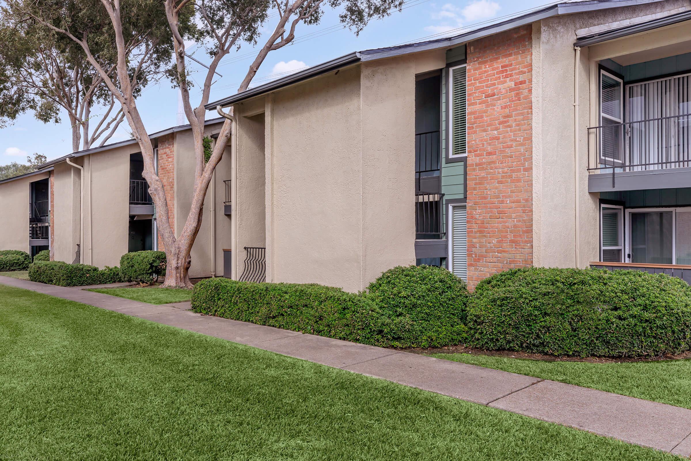 a house with a lawn in front of a brick building