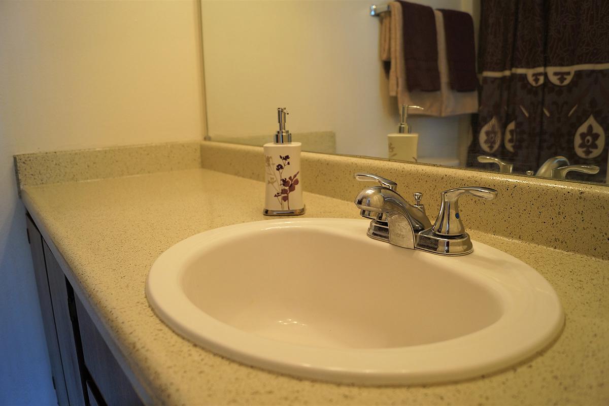 a white sink sitting under a mirror