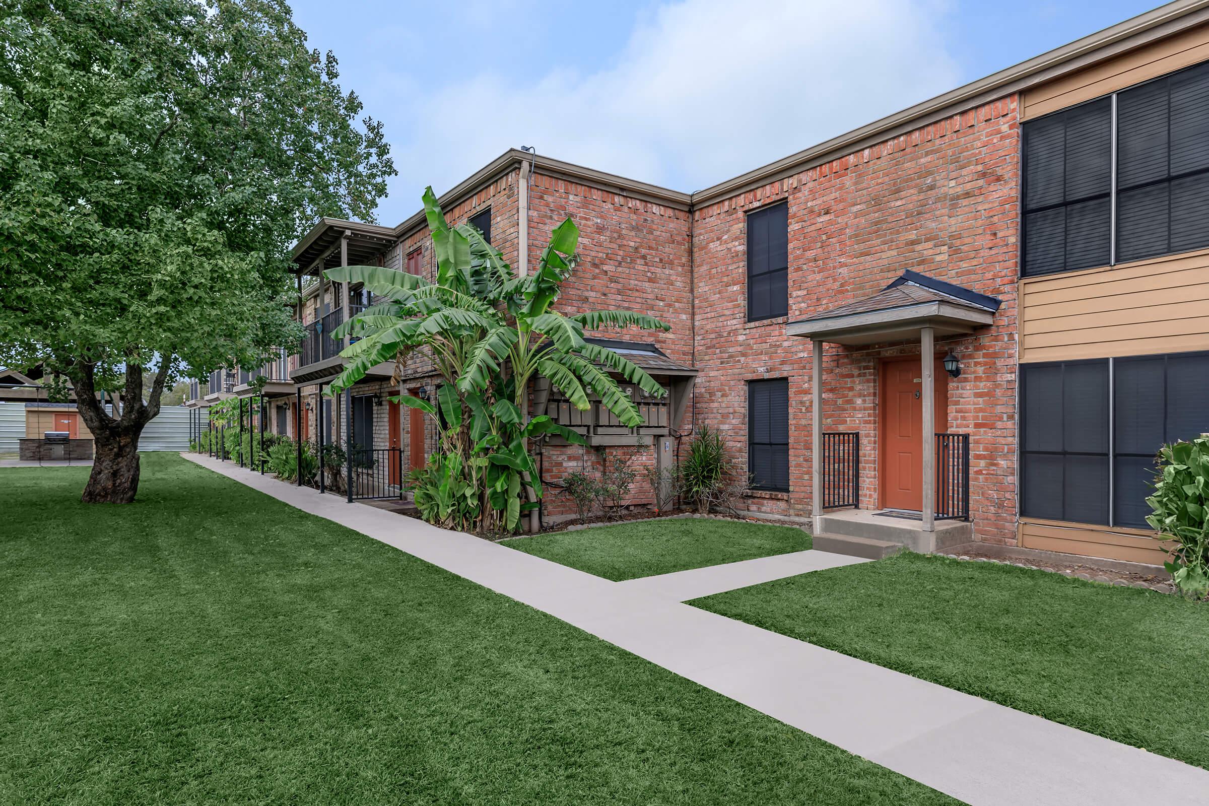 a large brick building with grass in front of a house