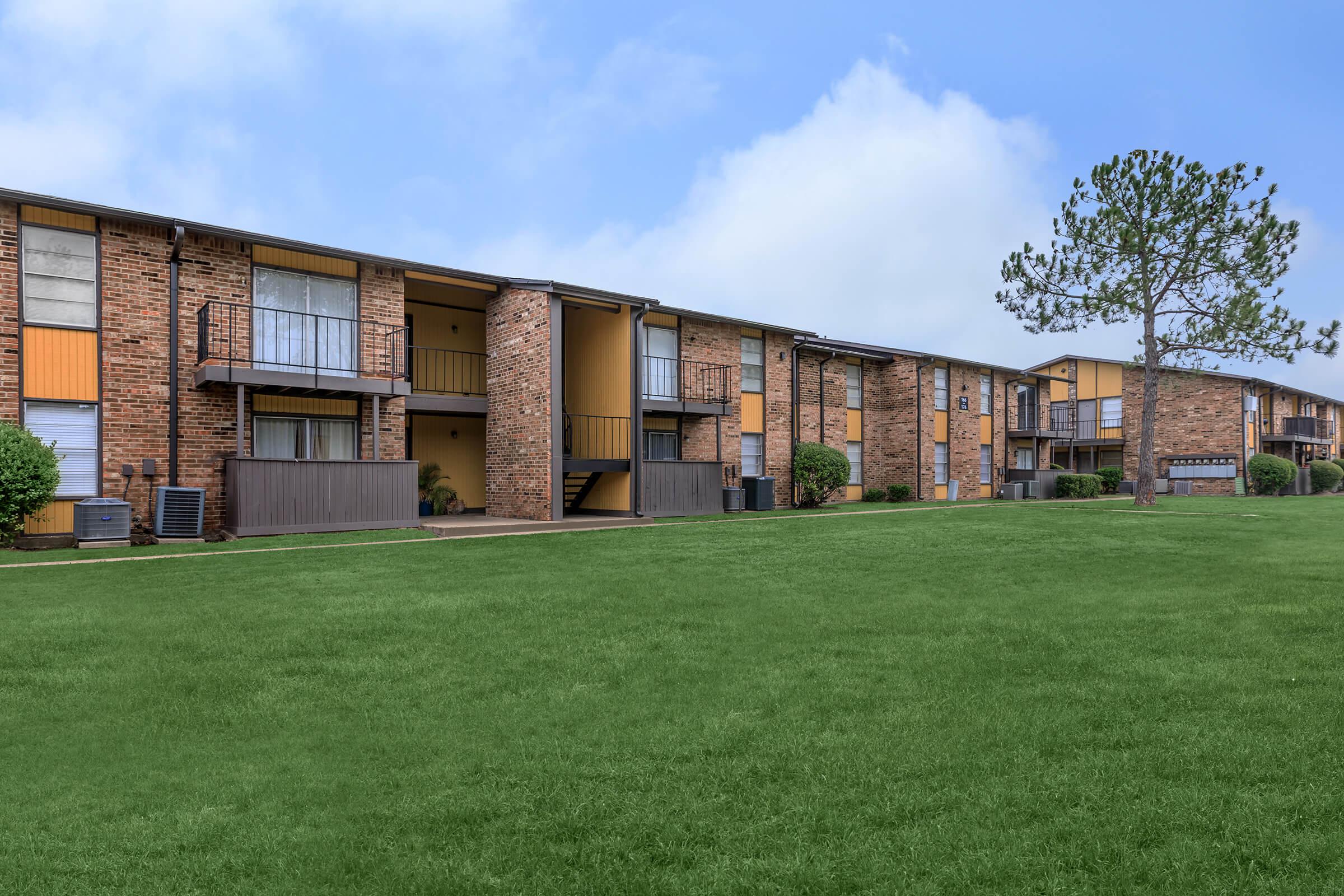 a large brick building with grass in front of a house