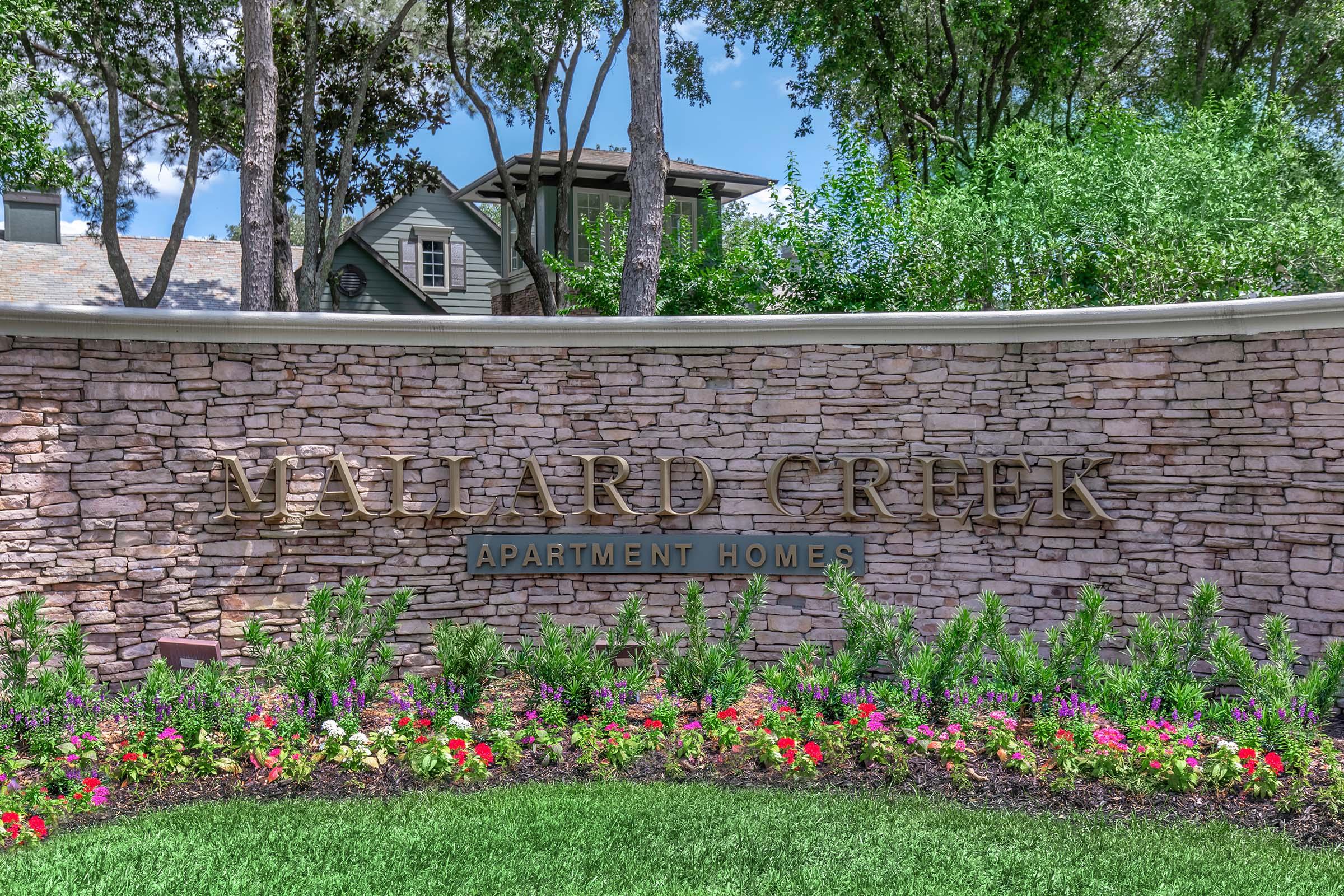 a close up of a flower garden in front of a brick building