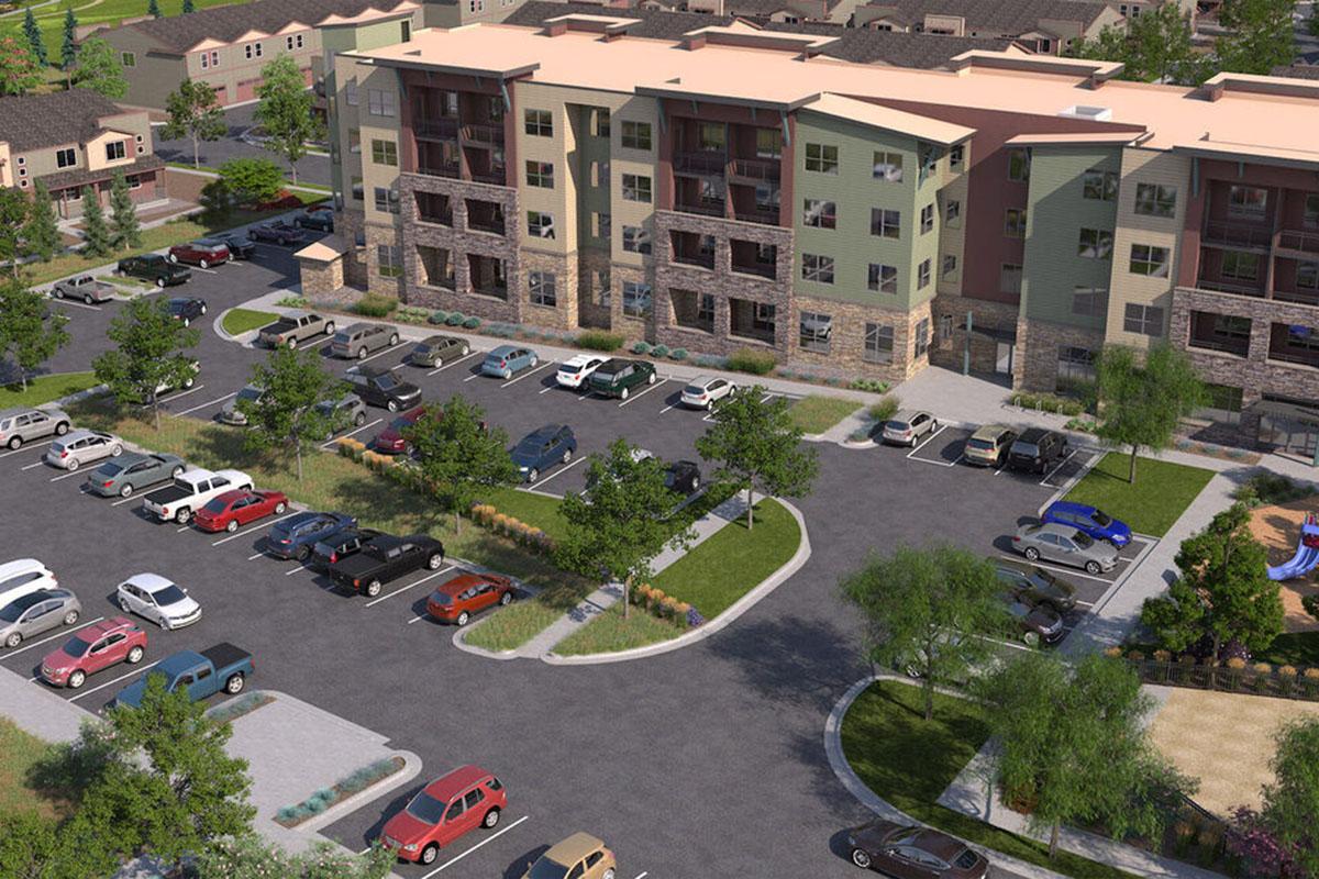 Aerial view of a modern apartment complex surrounded by a parking lot filled with cars. T