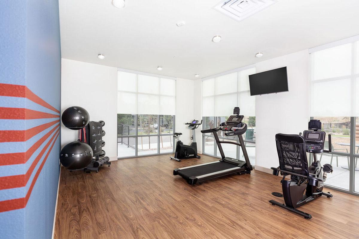 A modern gym area featuring exercise equipment including a treadmill, stationary bike, and weights.
