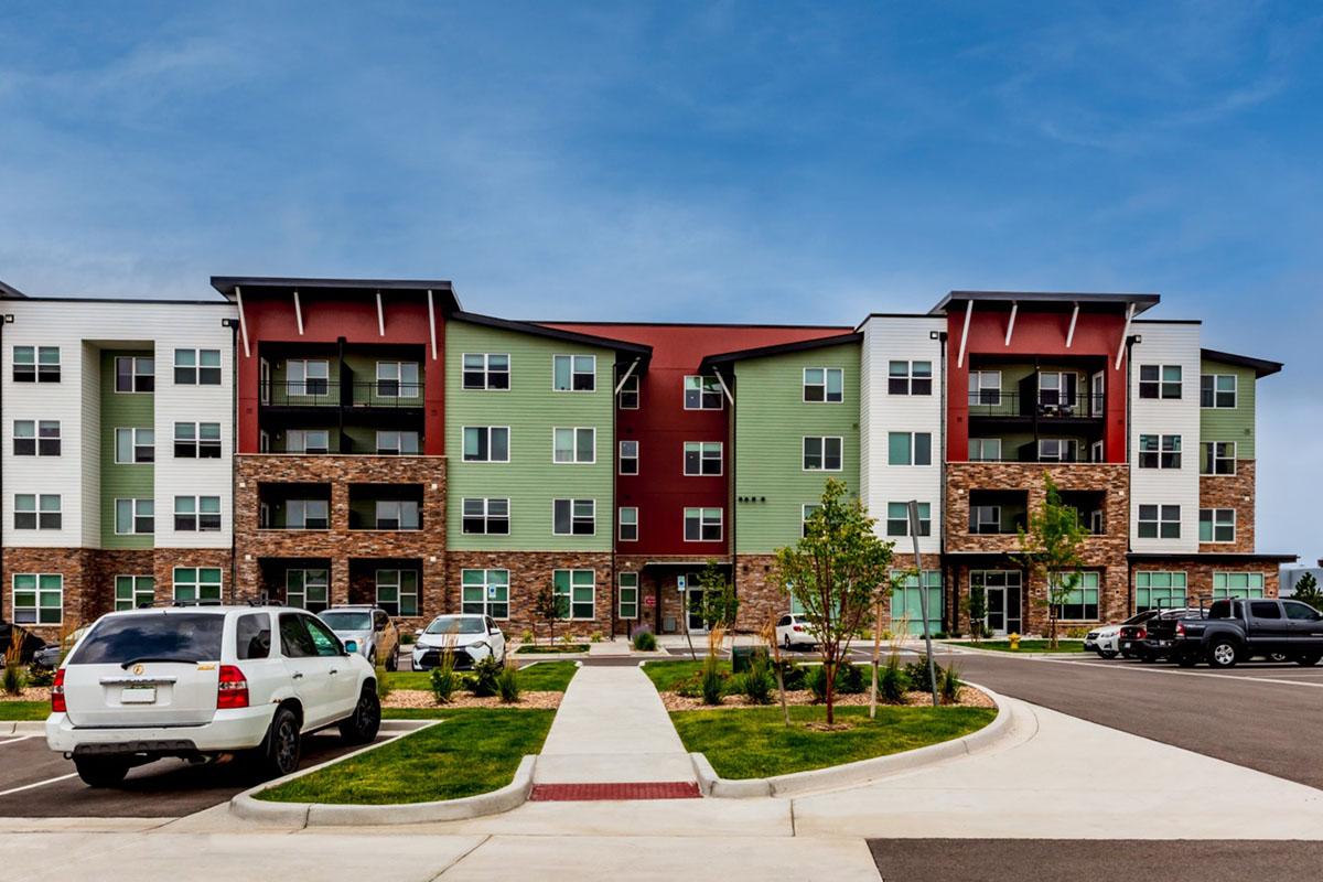 Modern multi-story apartment building with a mix of green, red, and white exterior.