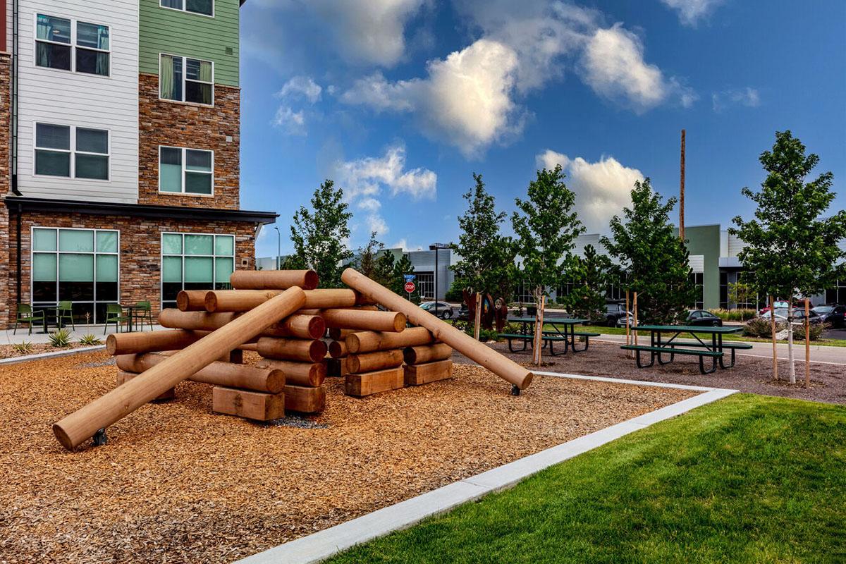An outdoor area featuring a mound of large wooden logs stacked in a creative formation.