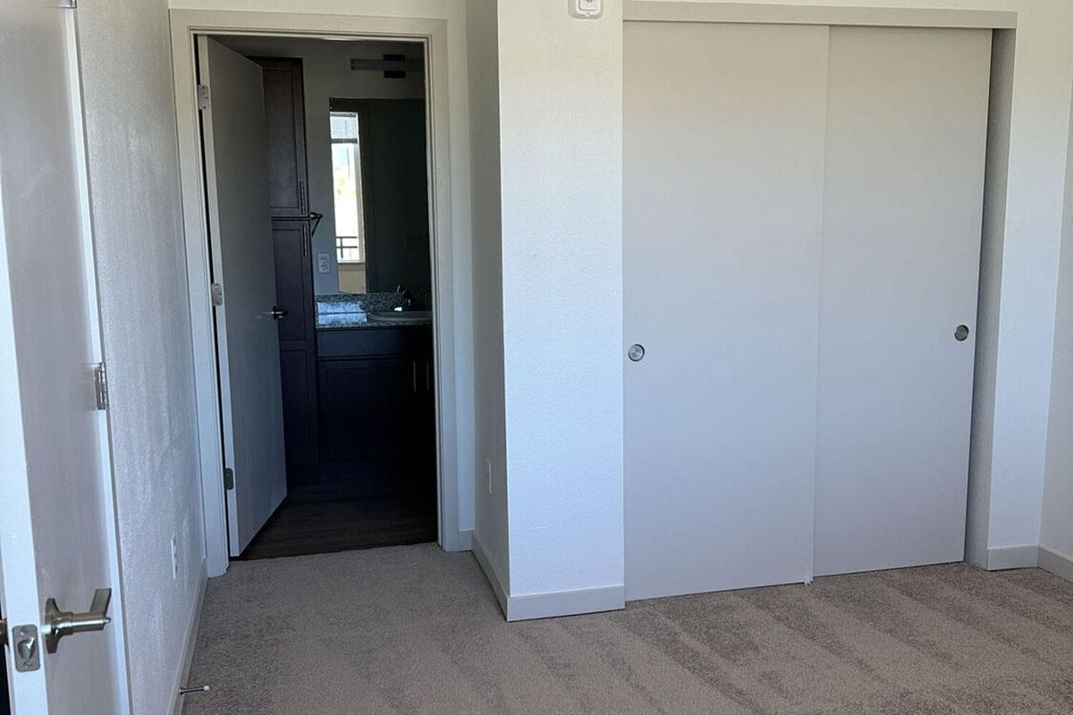 A view of a room showing a doorway leading to a bathroom with a mirror and sink visible.