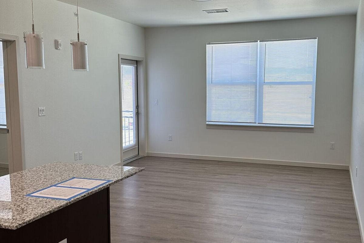 A bright, empty living space featuring light-colored walls and gray flooring.