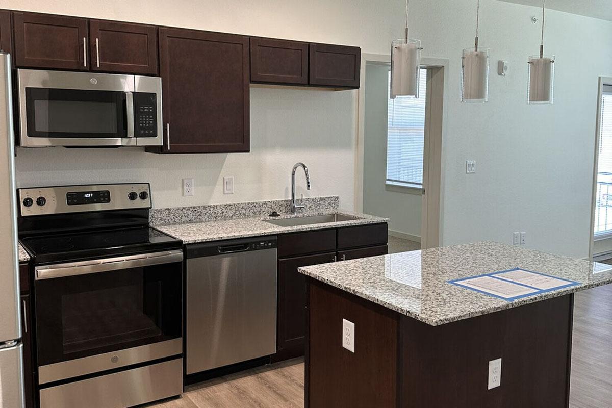 A modern kitchen featuring dark wood cabinets, stainless steel appliances including a microwave, oven, and dishwasher.