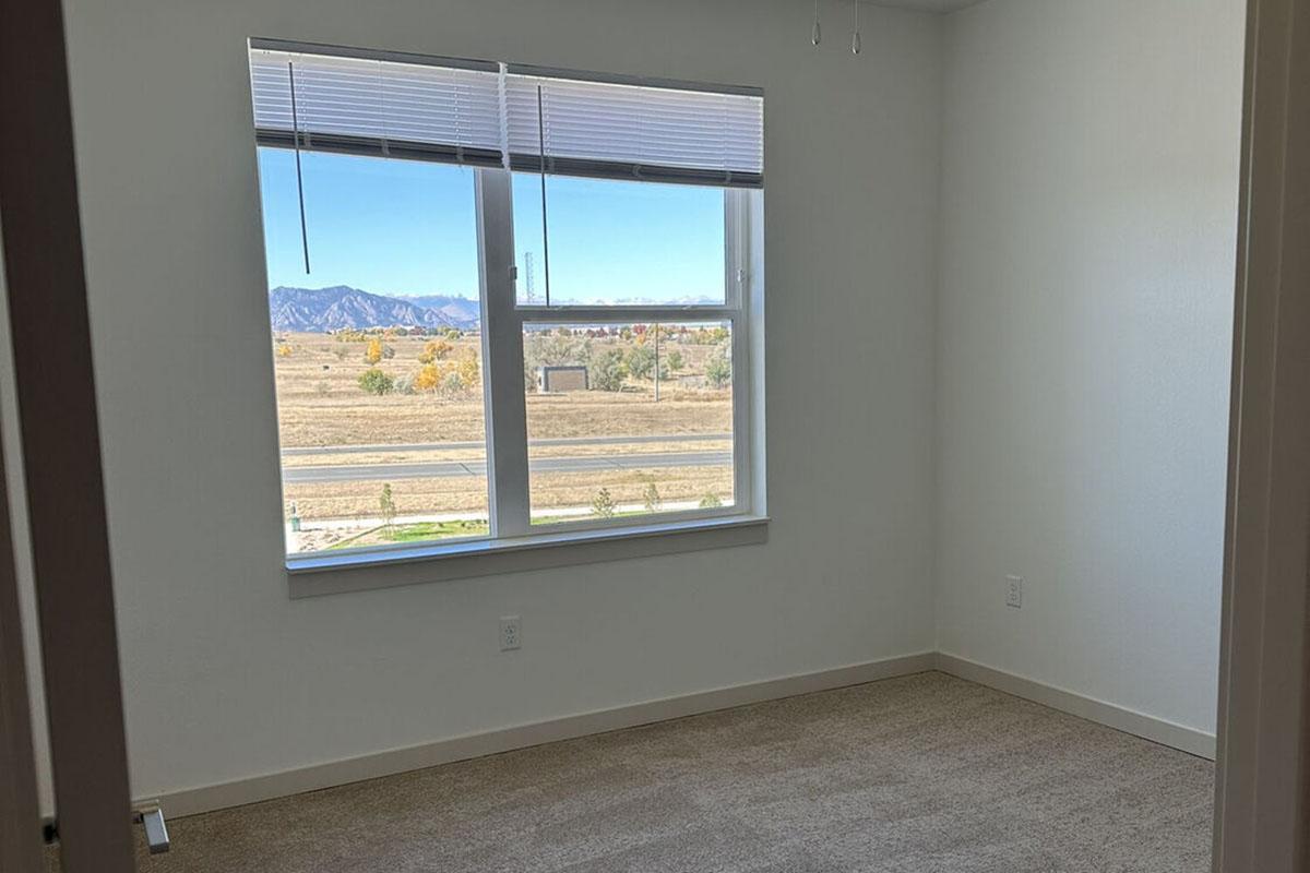 A vacant room with light-colored walls and carpet.