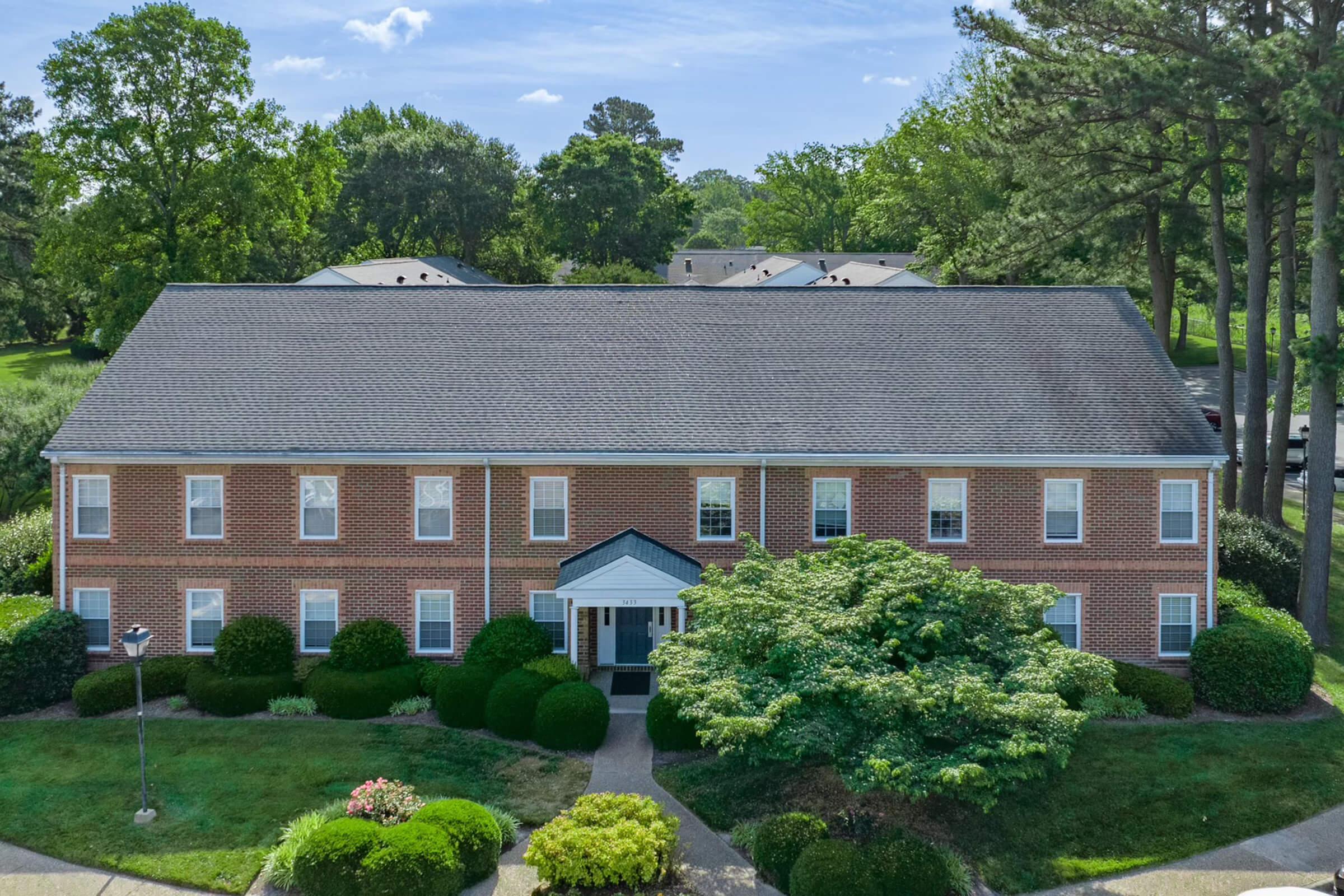 a large brick building with grass in front of a house