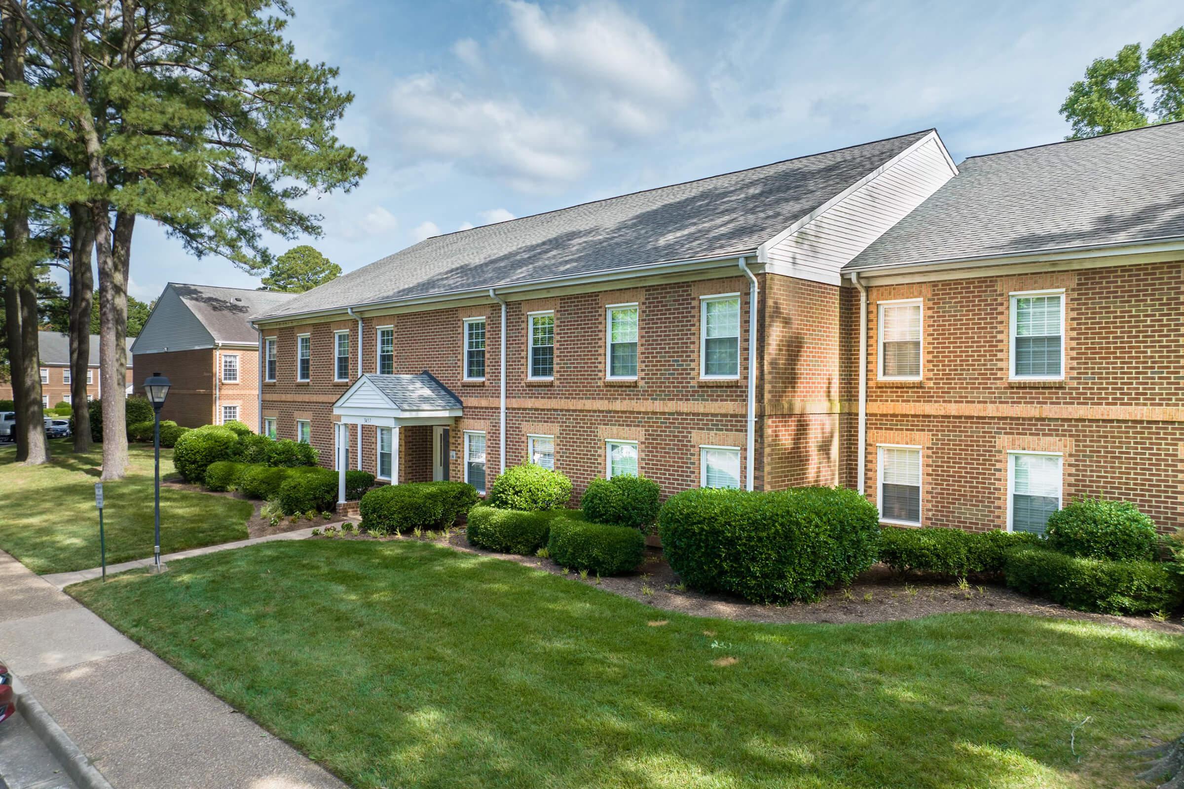 a large brick building with grass in front of a house