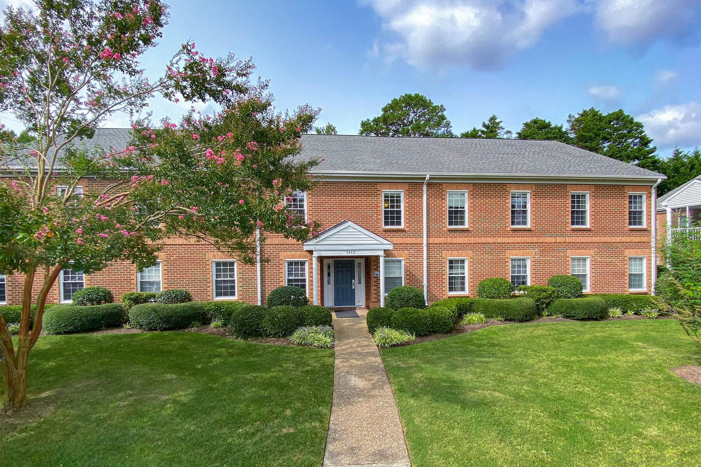 a house with a lawn in front of a brick building