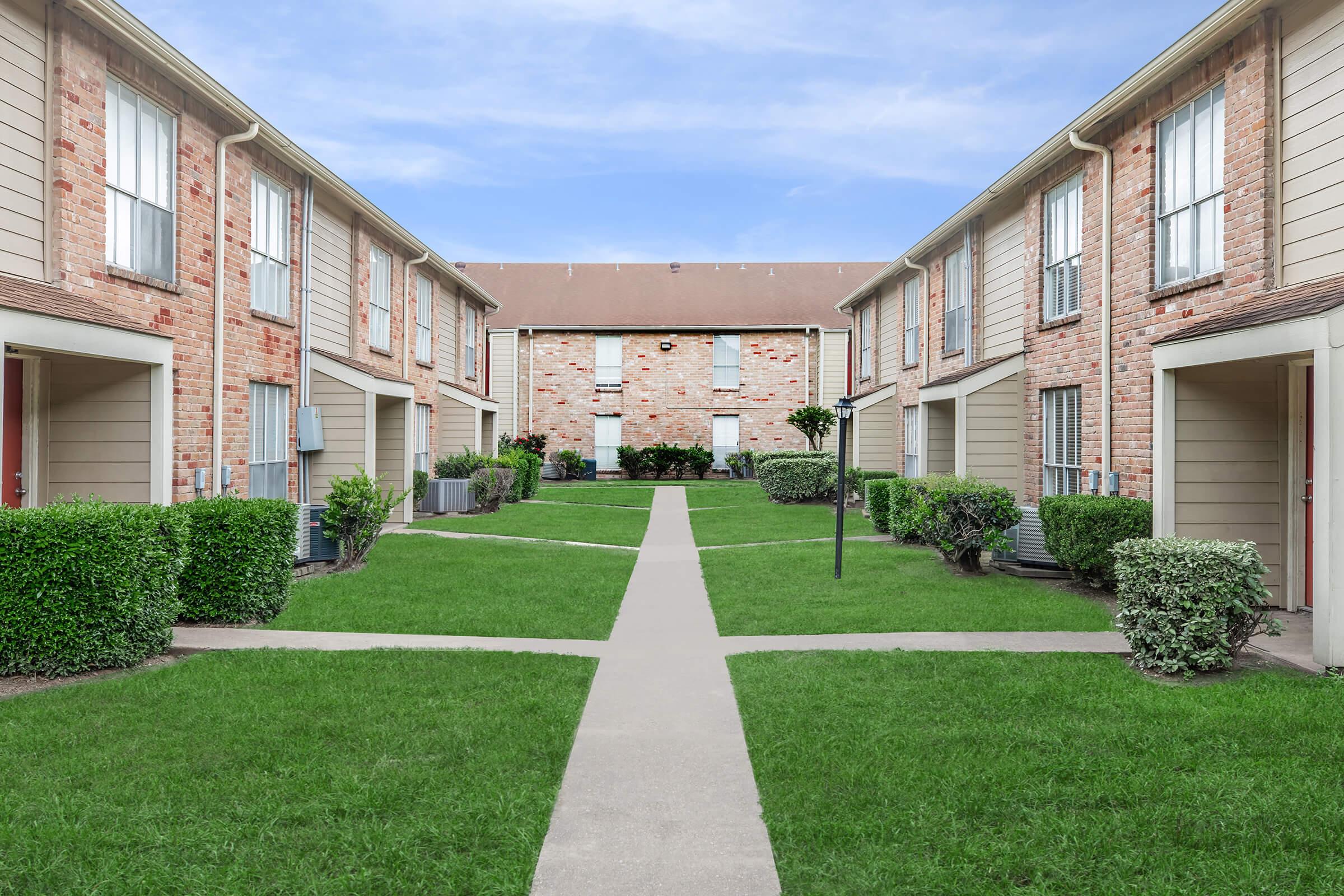 a house with a lawn in front of a brick building