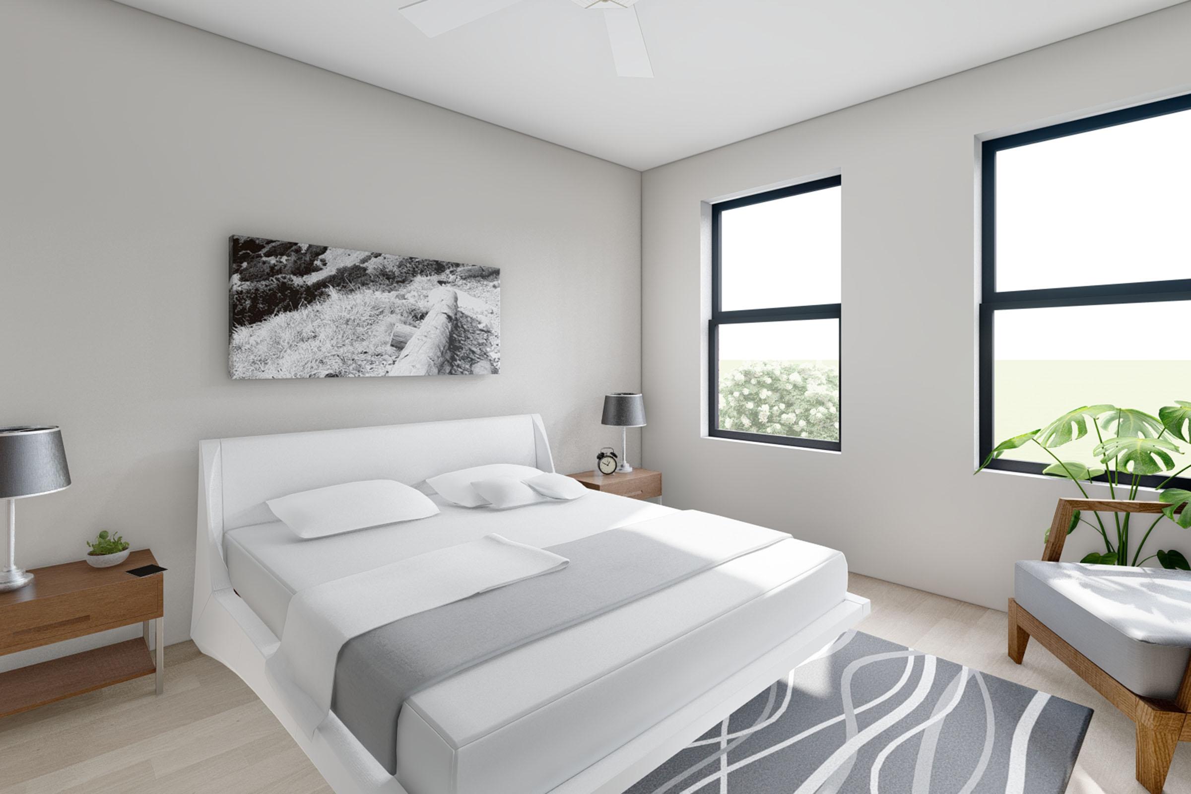 A modern bedroom featuring a white bed with gray bedding, two windows allowing natural light, and a landscape photograph on the wall. There are bedside tables with lamps, a plant beside a cozy chair, and light wood flooring, creating a clean and serene atmosphere.