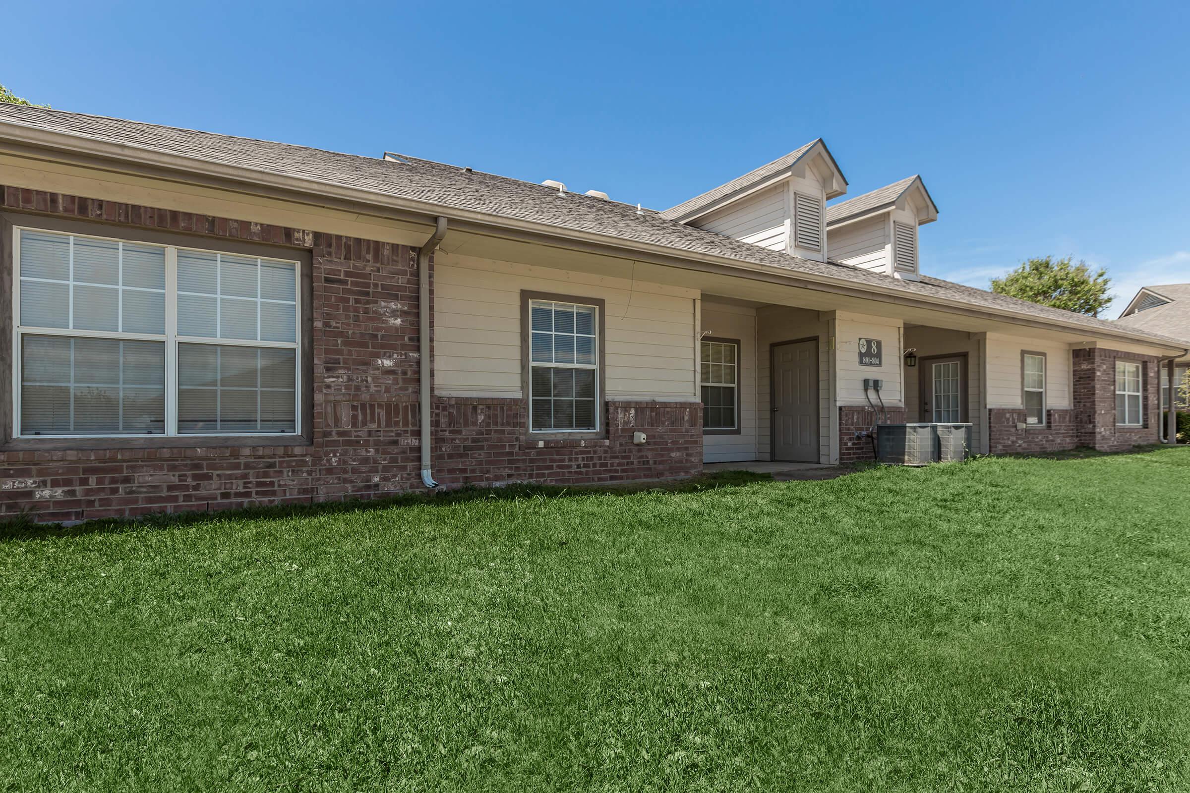 a house with a lawn in front of a brick building