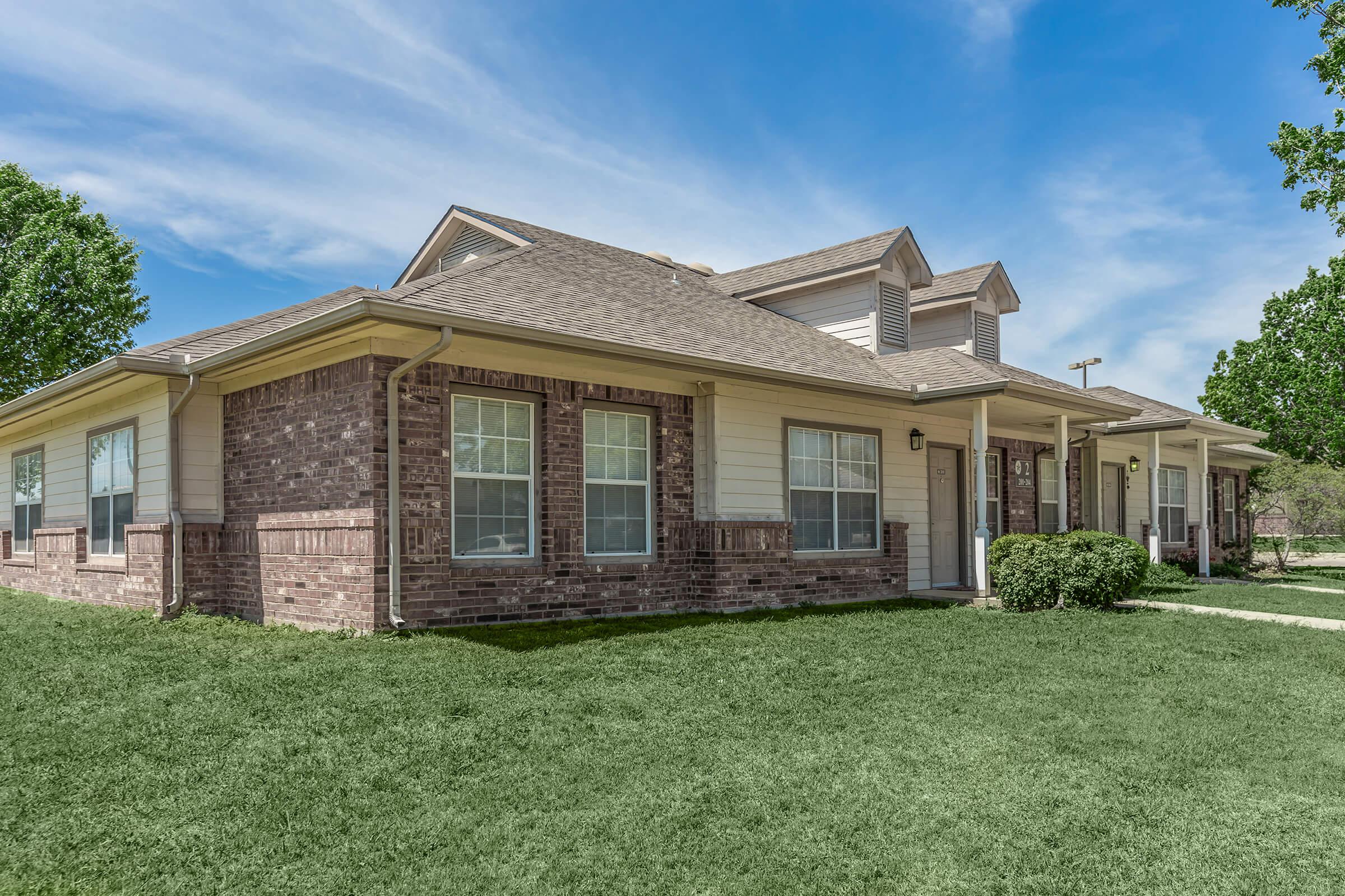 a large brick building with grass in front of a house