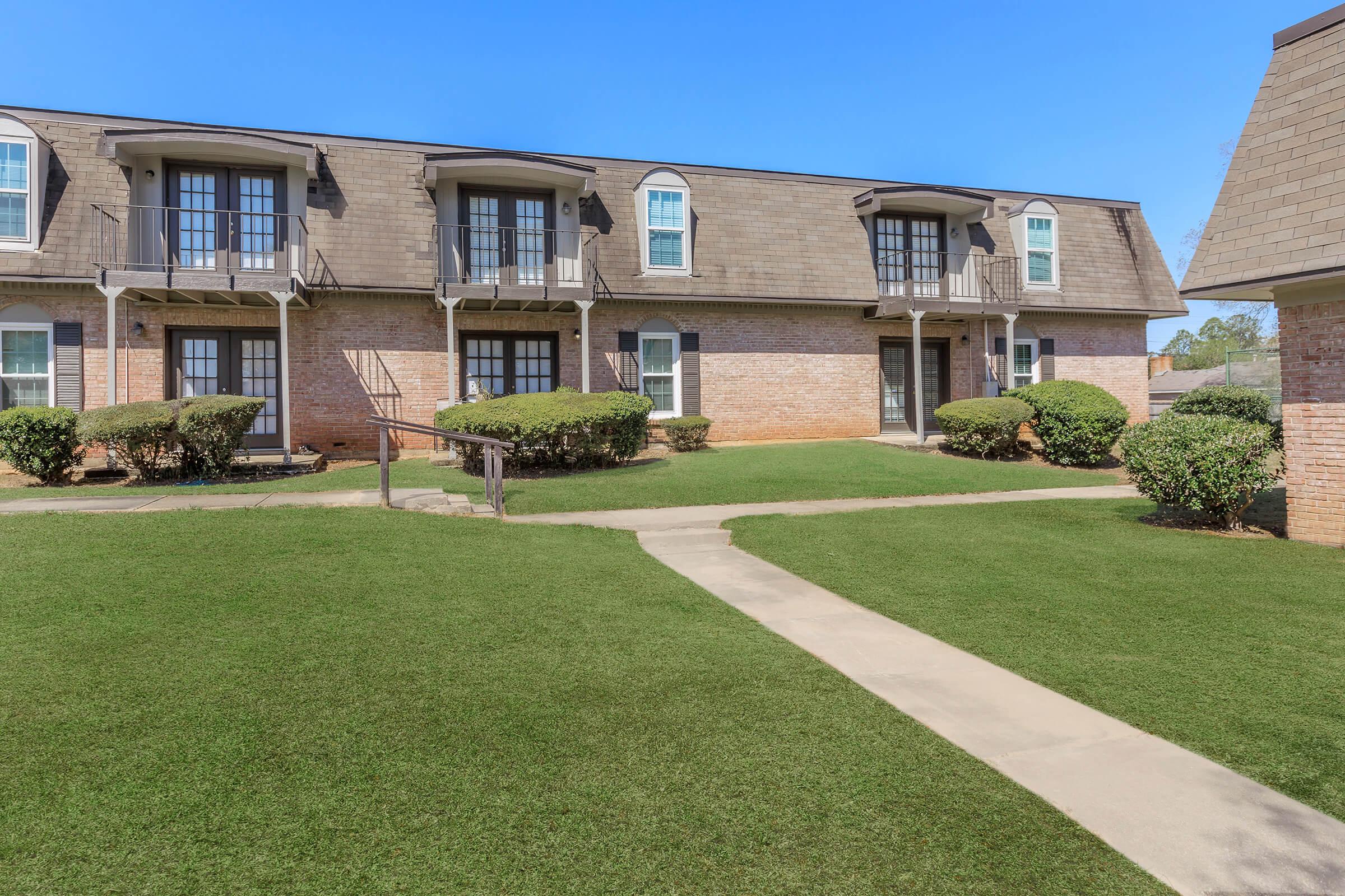 a large brick building with green grass in front of a house