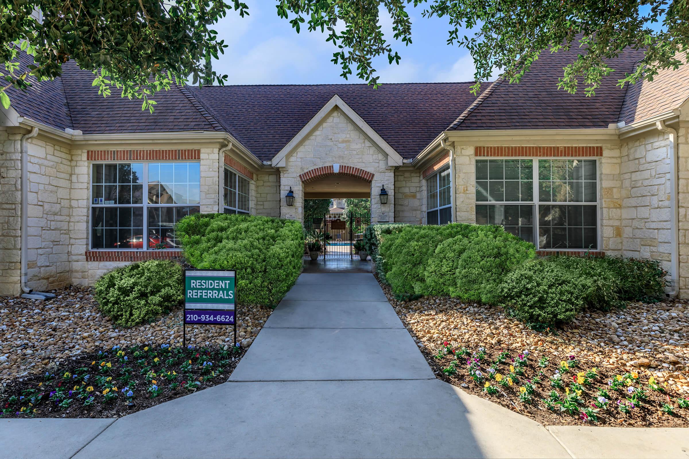 a house with bushes in front of a brick building