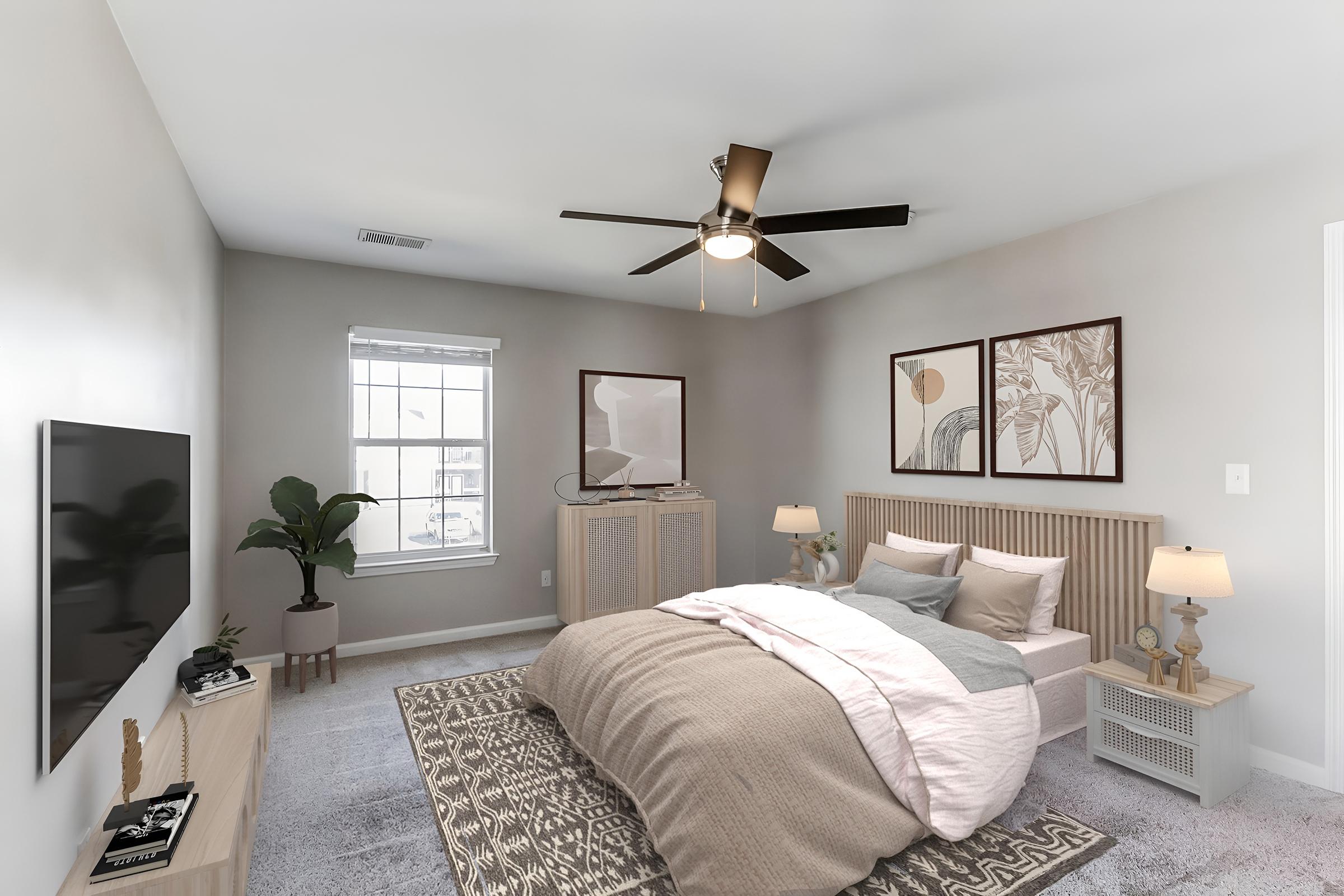 Cozy bedroom featuring a bed with soft pink and gray bedding, a ceiling fan, and two lamps on bedside tables. Decor includes framed botanical art on the walls, a TV mounted on the wall, and a potted plant in the corner. The overall color scheme is neutral with touches of warm tones.