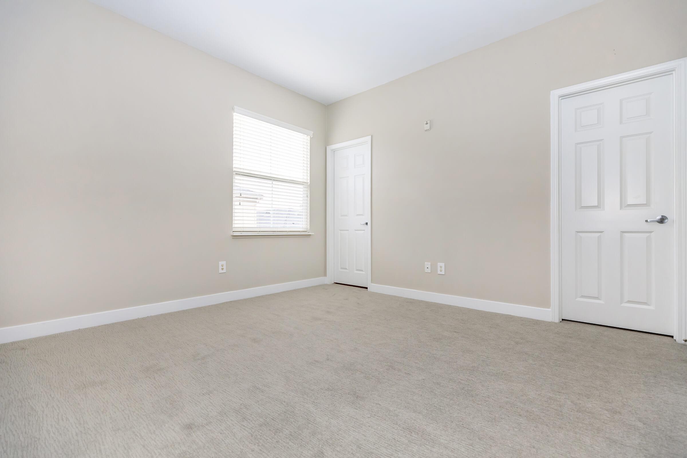 Unfurnished carpeted bedroom with closed doors