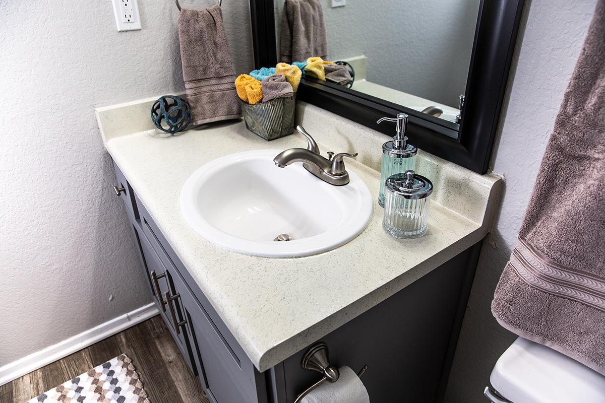 a white sink sitting under a mirror