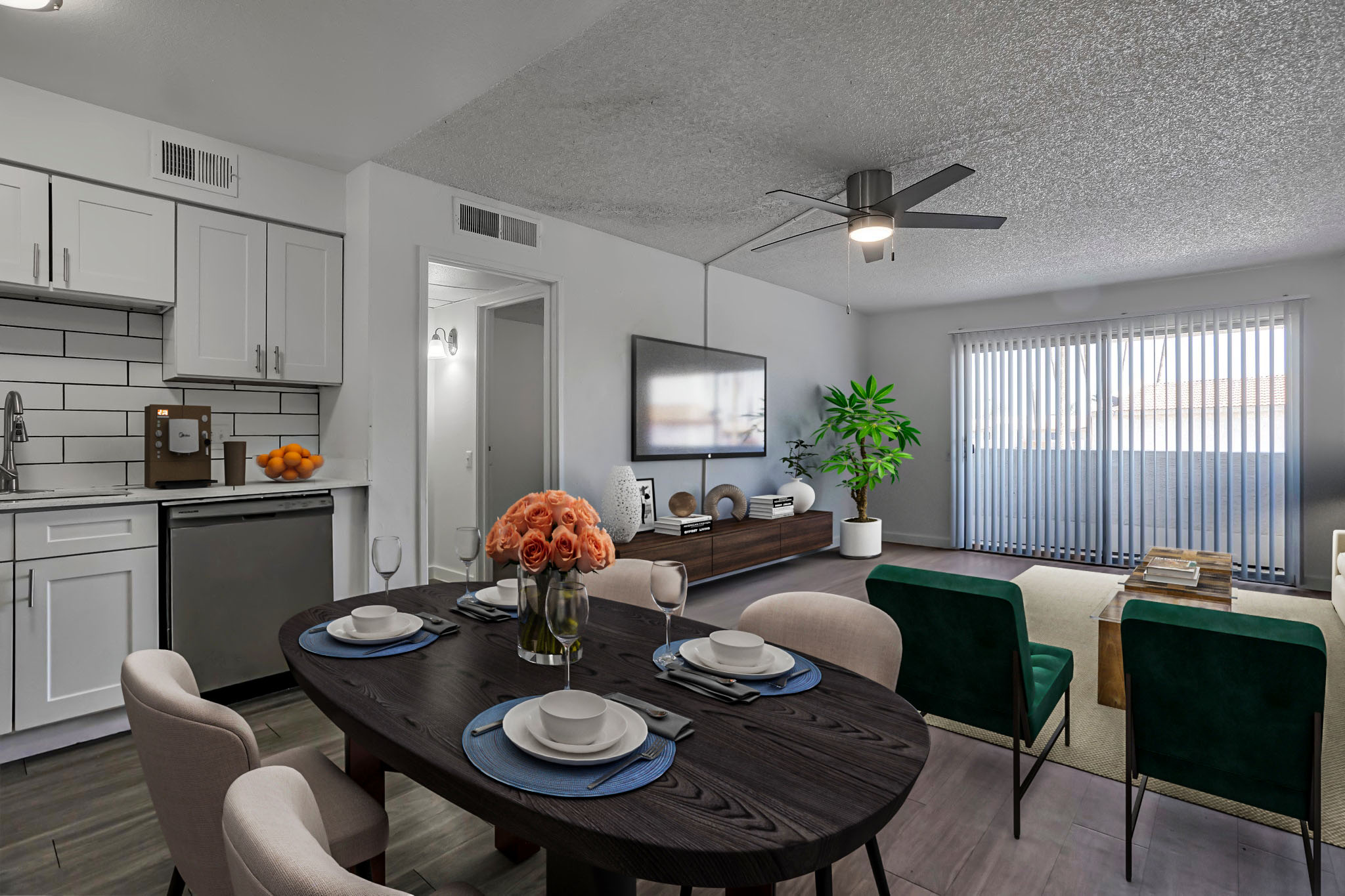 Modern living space featuring a dining area with a round table set for four, a stylish living room with a sofa and TV, and a kitchen with contemporary cabinetry. Brightly lit with large windows, the decor includes plants and decorative items, creating a warm and inviting atmosphere.