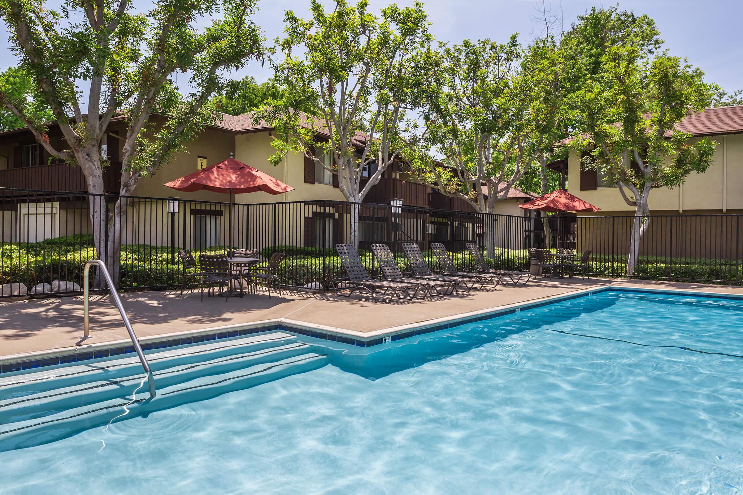 Country Hills Apartment Homes community pool with tables and red umbrellas