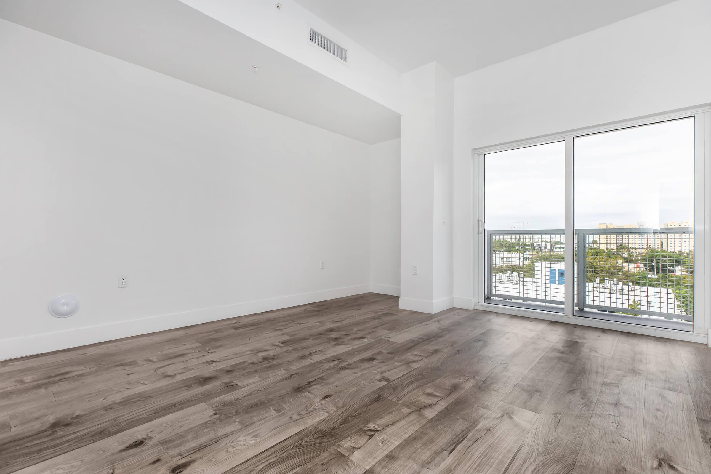 1 bedroom apt with brown wood vinyl floor, living room looking to the patio