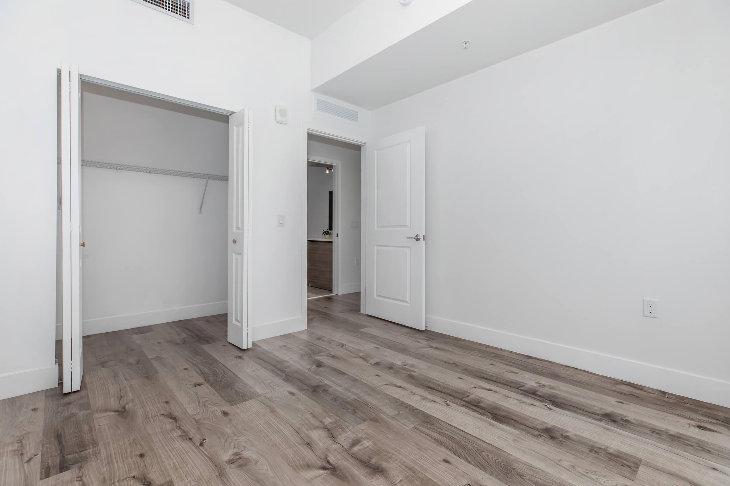 Bedroom view with brown wood flooring, closet space and bathroom outside the bedroom