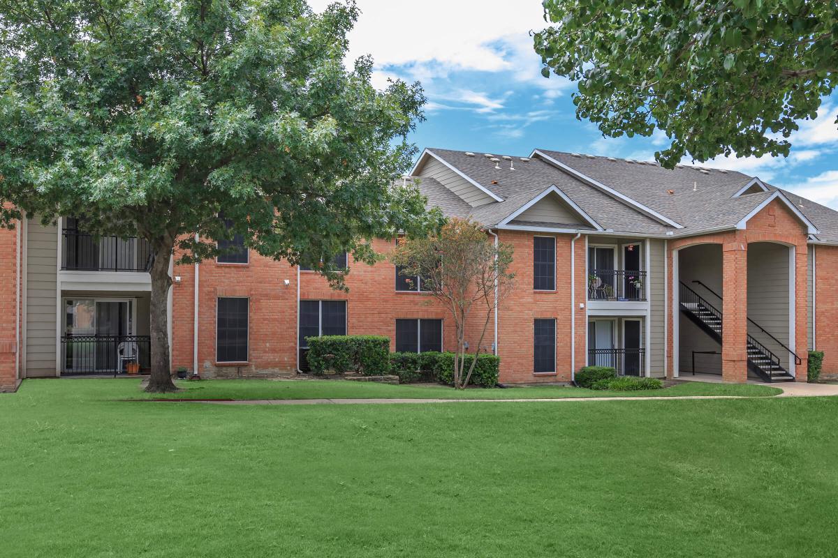 a large brick building with green grass in front of a house