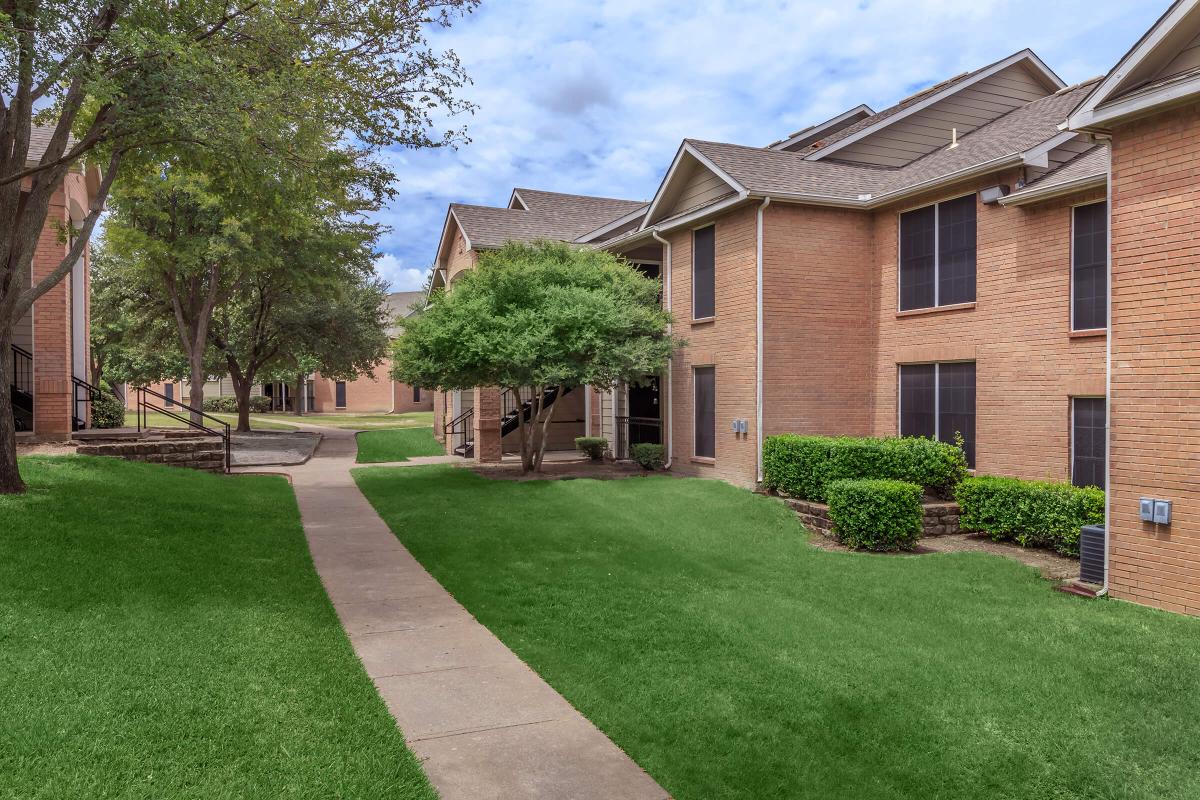 a large brick building with green grass in front of a house