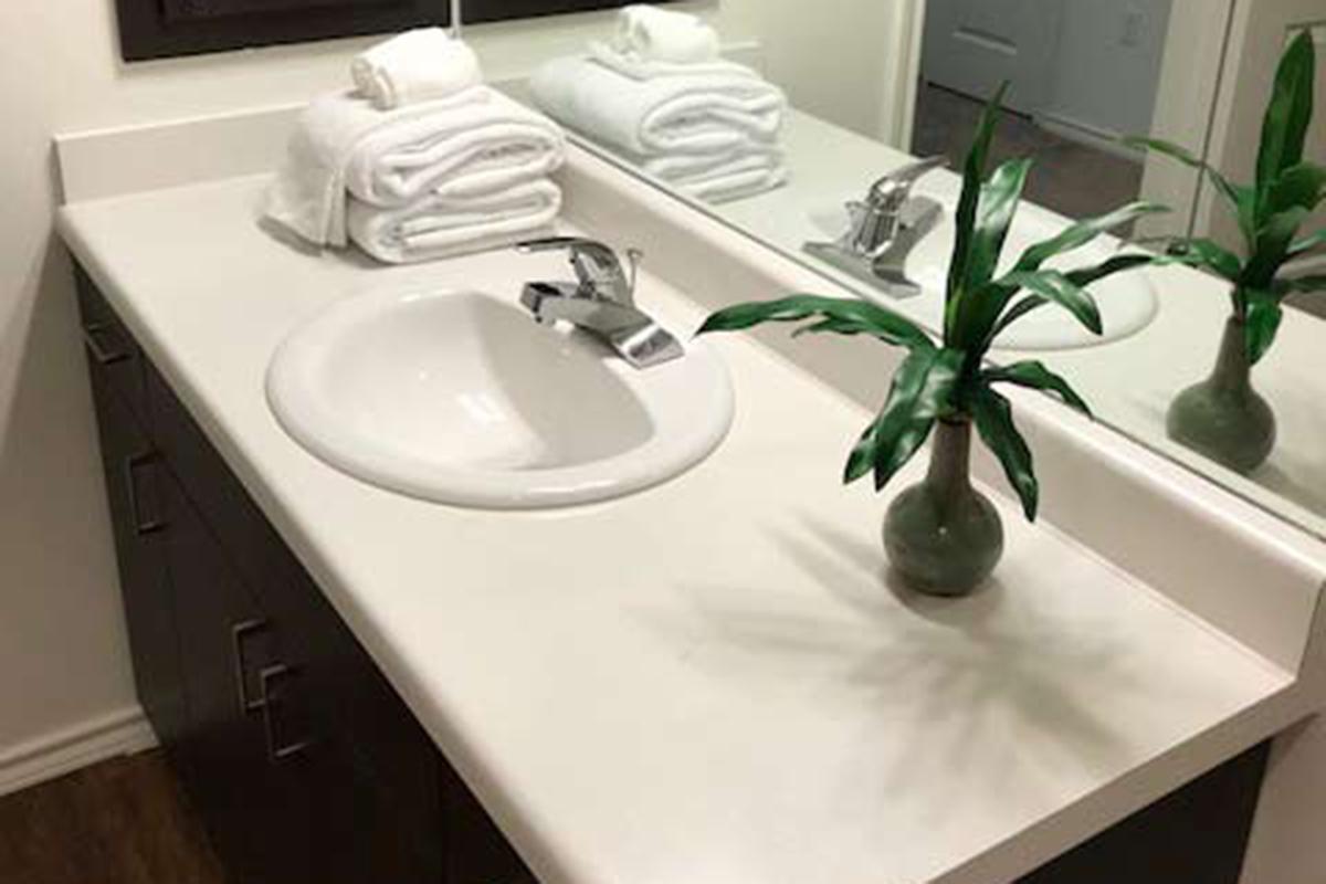 a white sink sitting next to a vase of flowers on a table