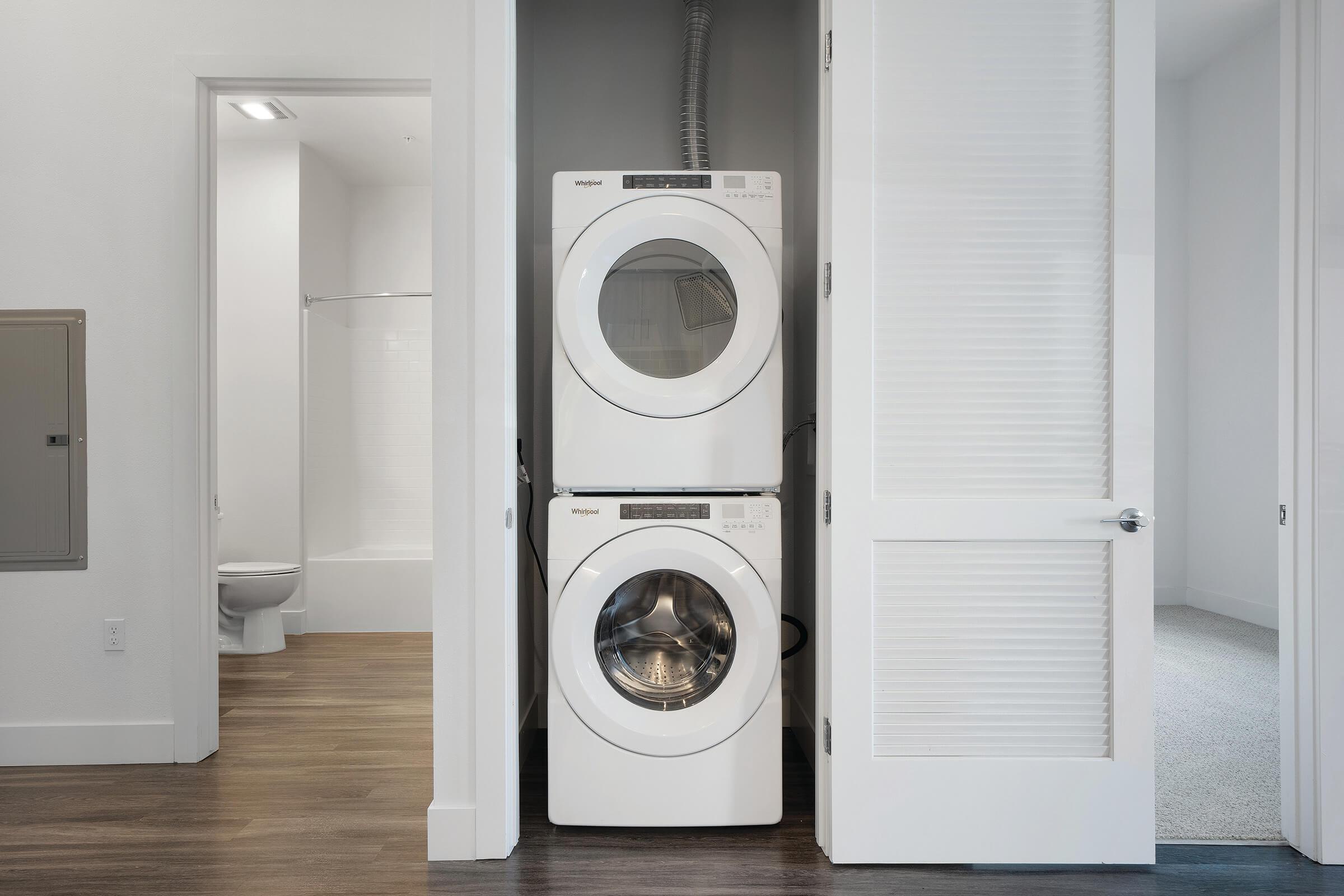 Stacked washer and dryer with bathroom in background