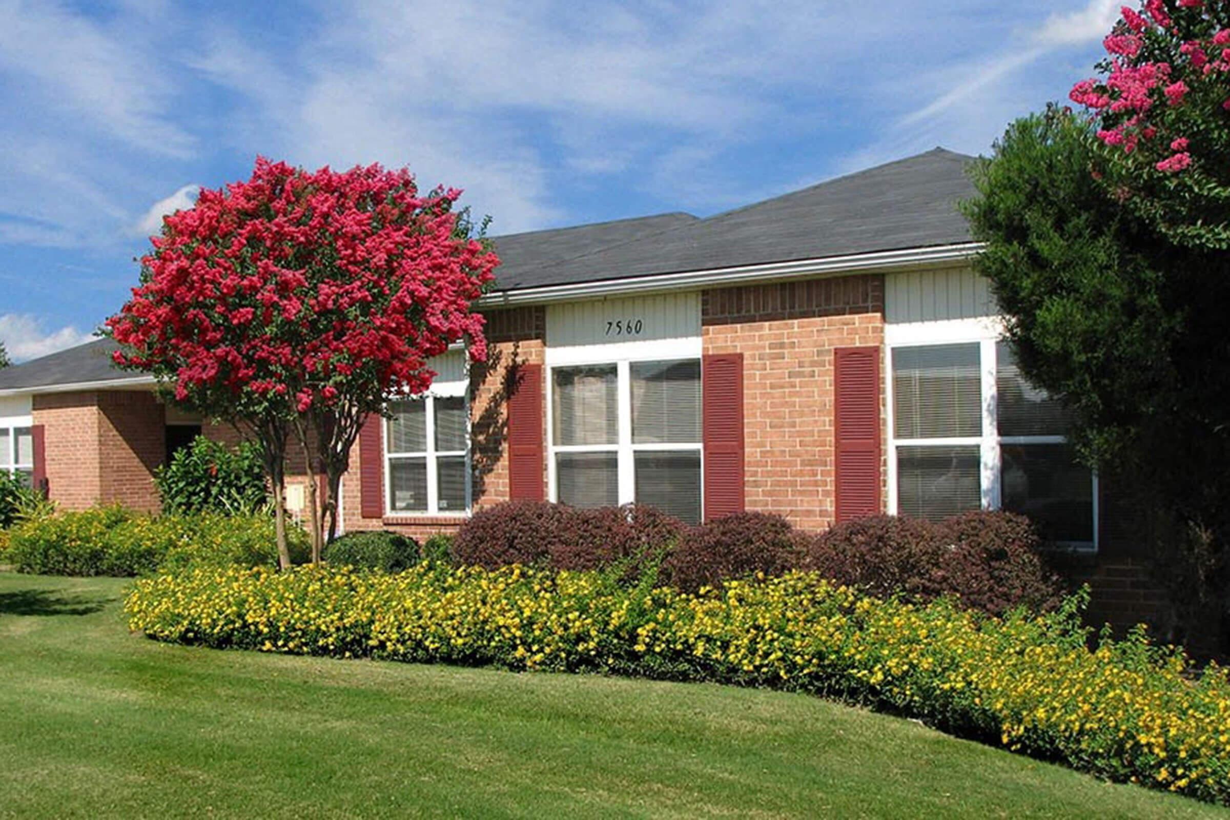 a house with bushes in front of a brick building