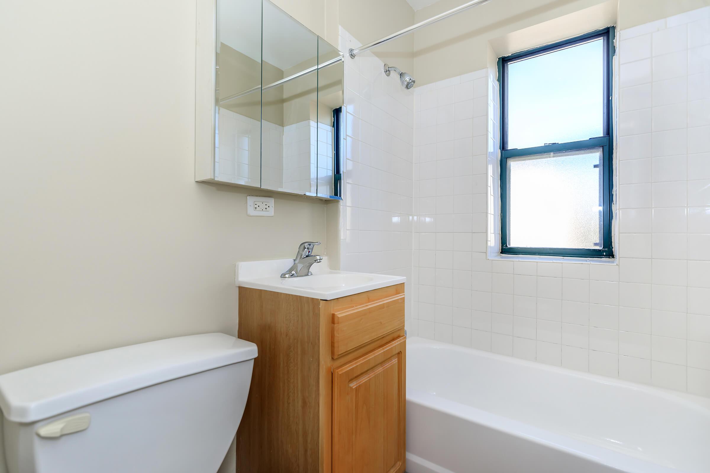 a room with a sink and a white tub sitting next to a window