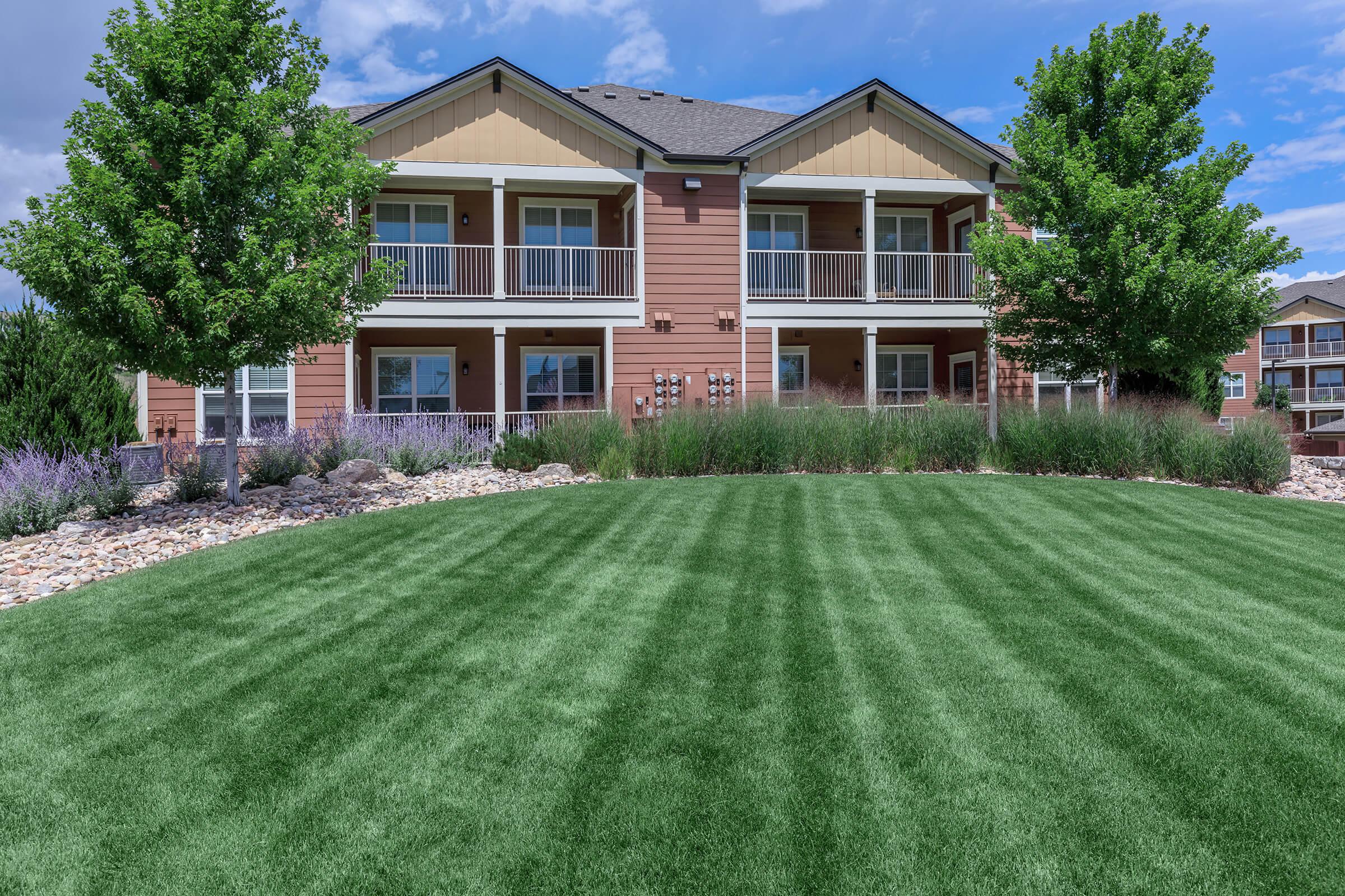 a large brick building with green grass in front of a house