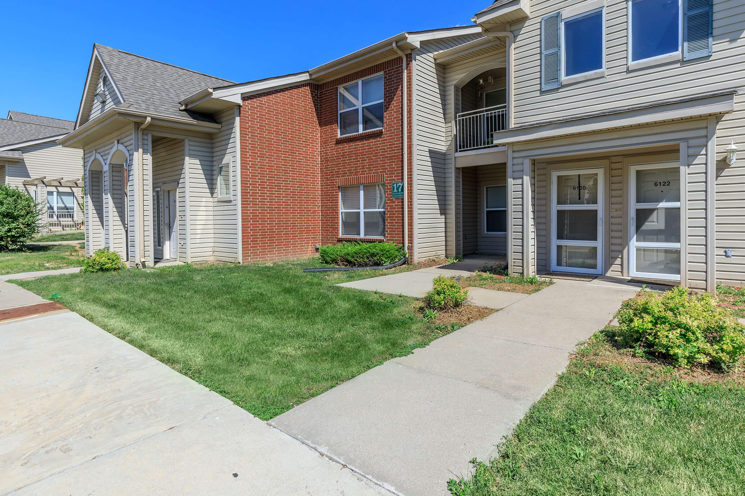 a large brick building with grass in front of a house