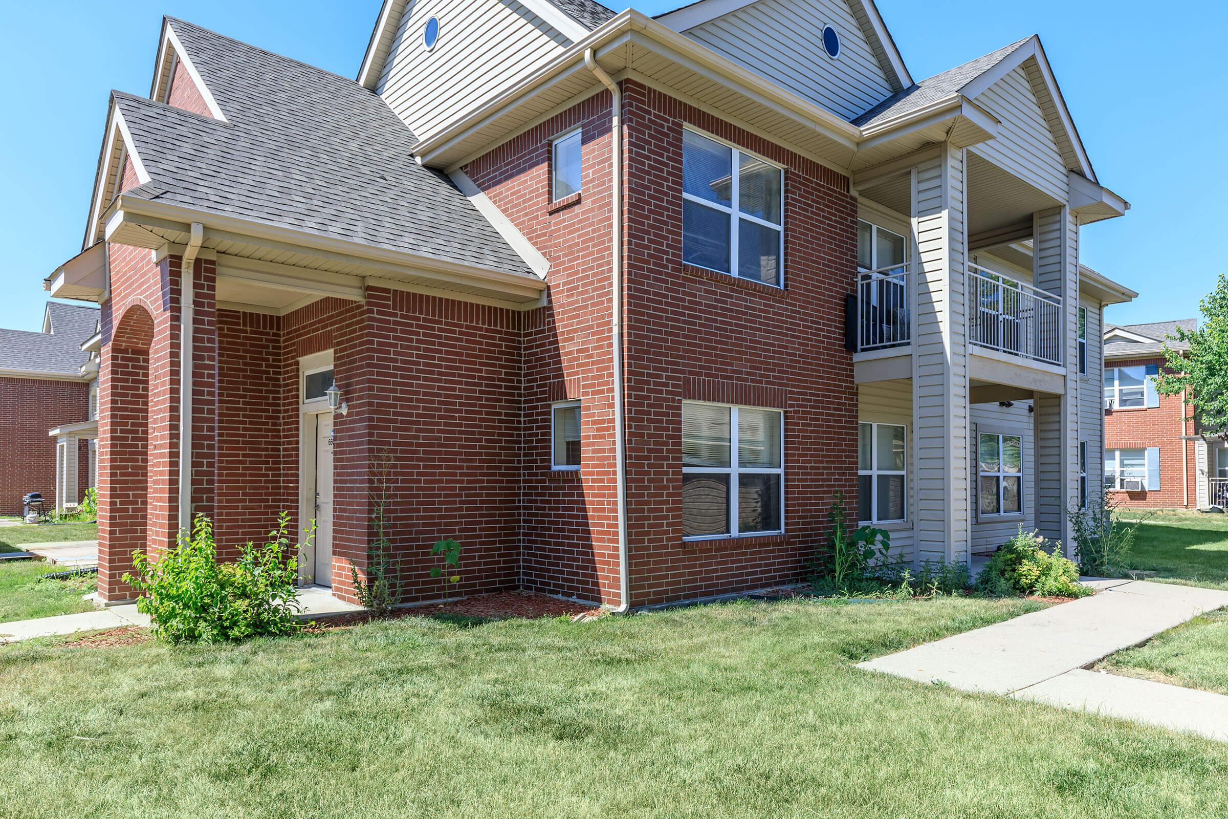 a house with a lawn in front of a brick building