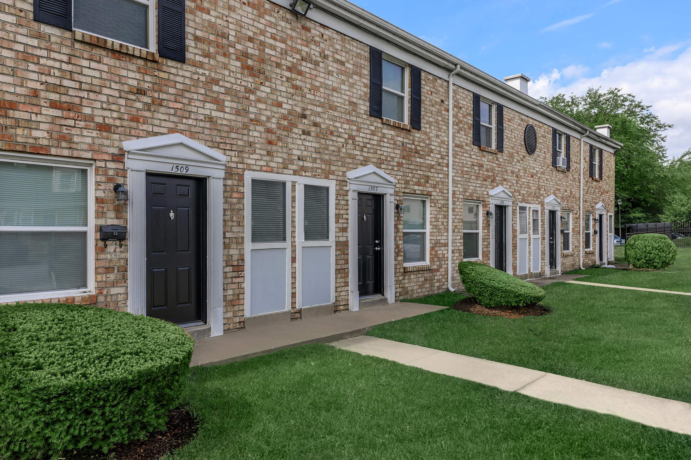 a house with a lawn in front of a brick building