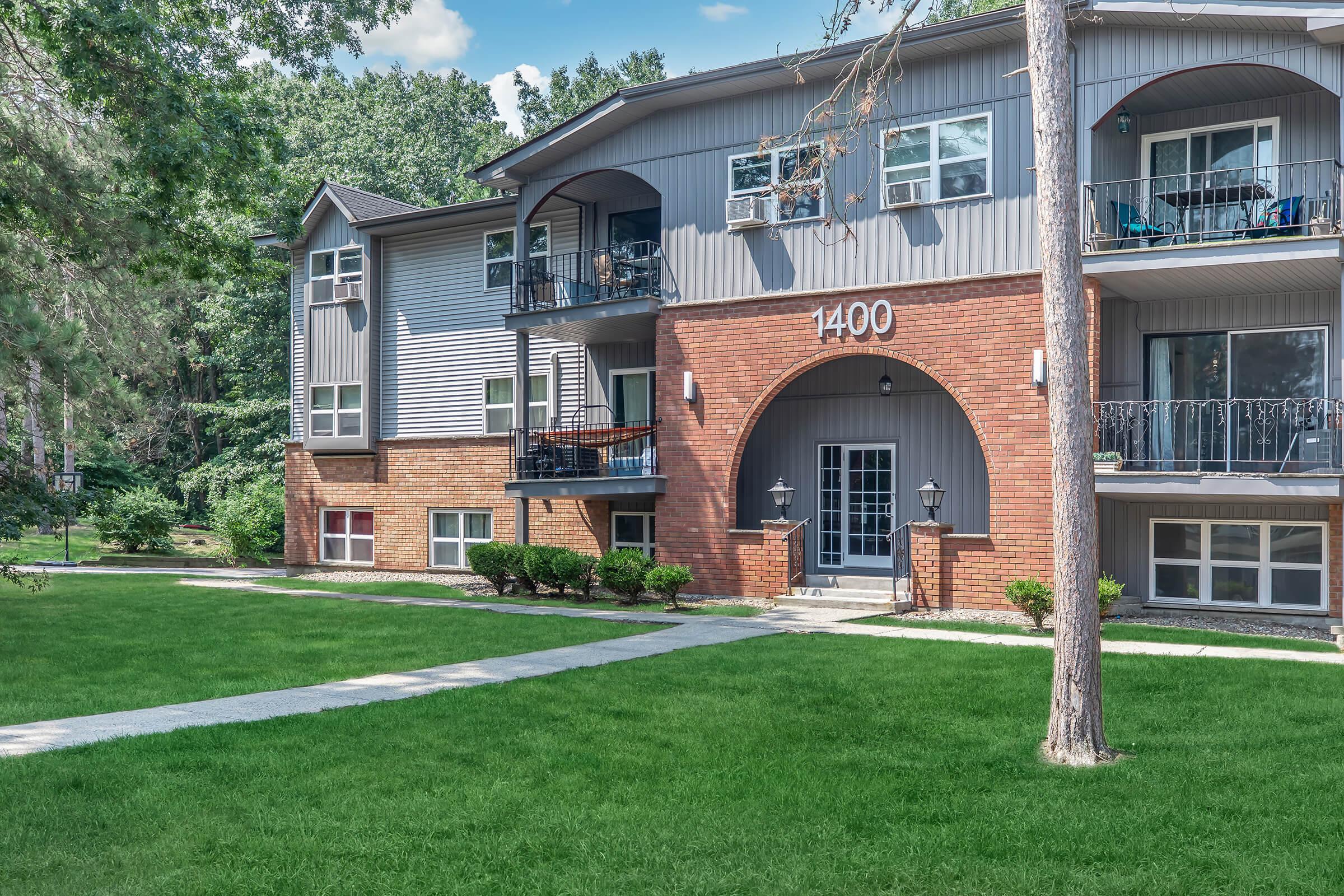 a house with a lawn in front of a brick building