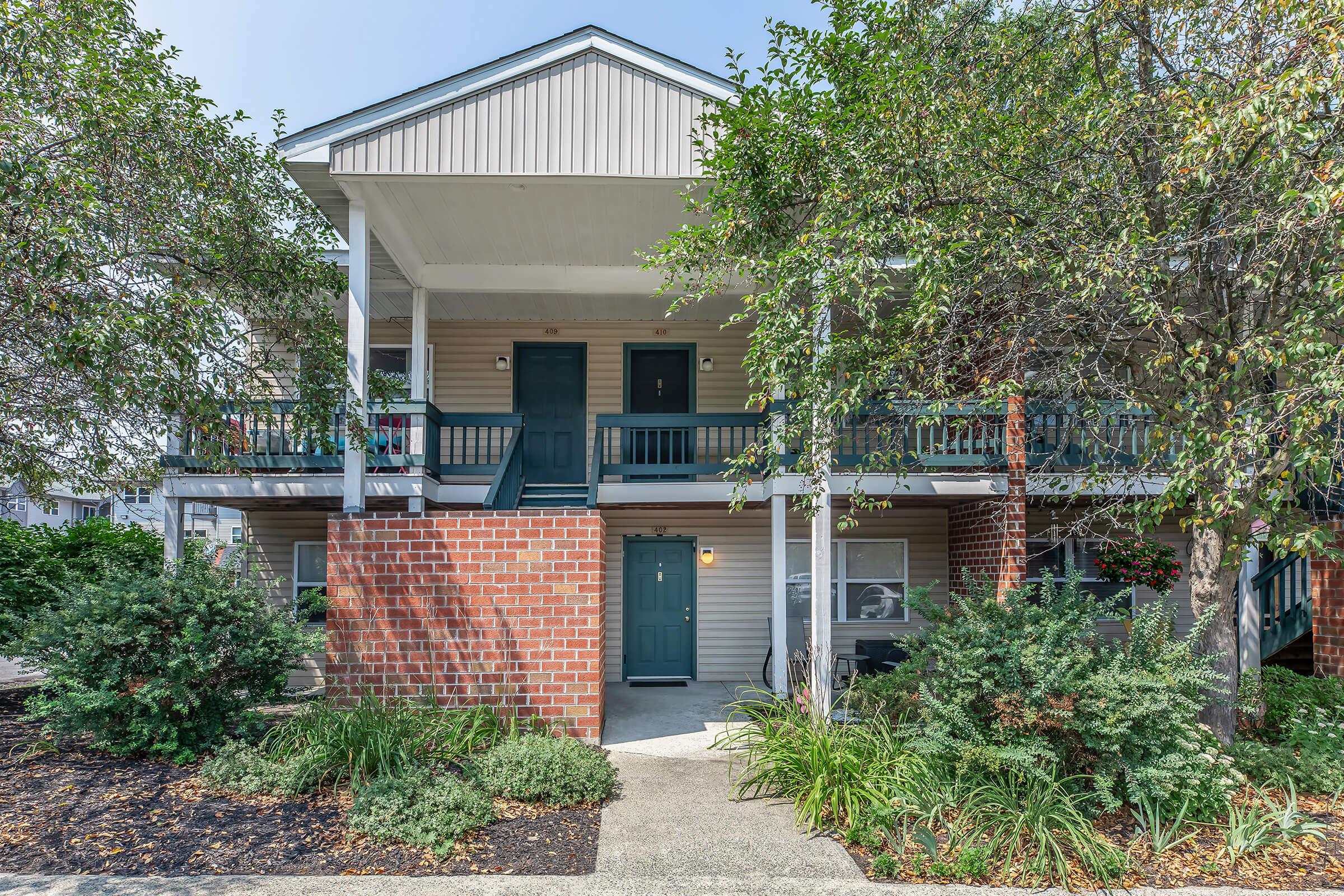 a house with bushes in front of a brick building