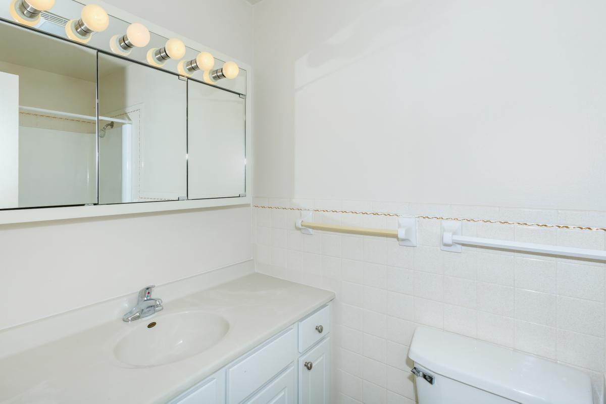 a white sink sitting under a mirror