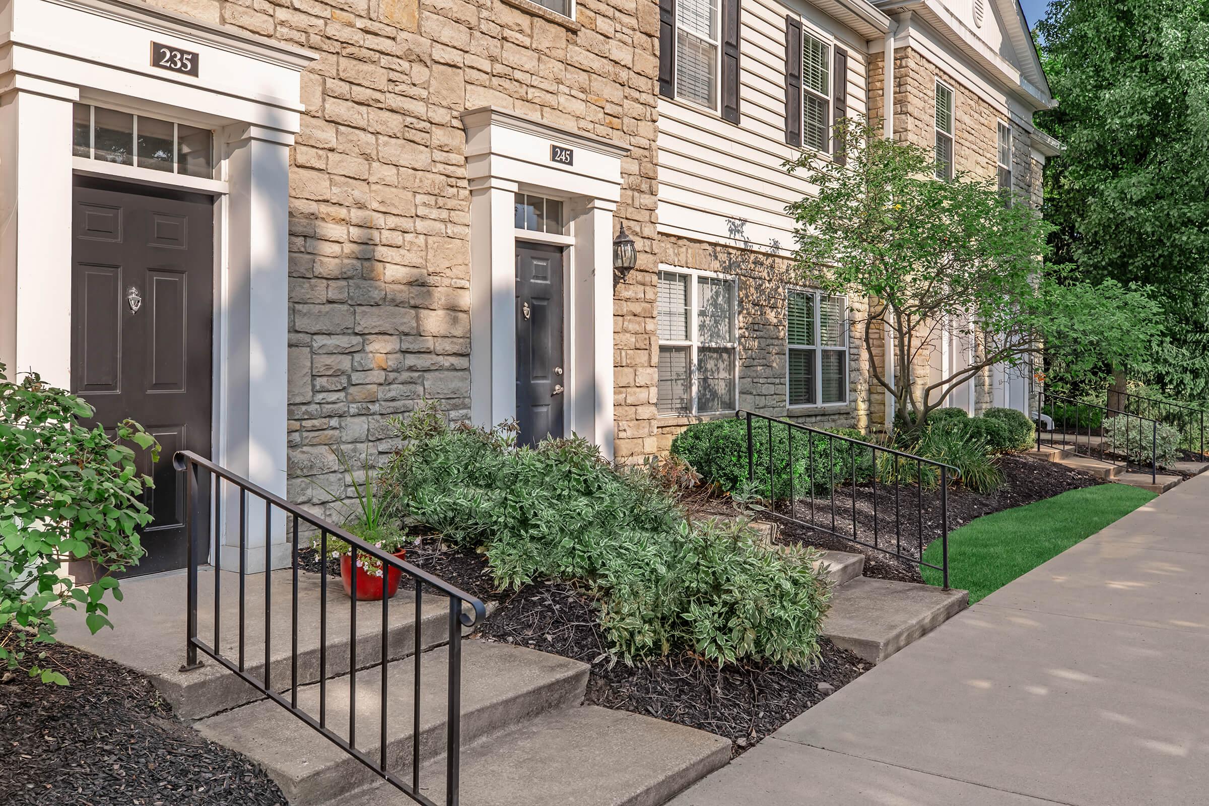 a house with bushes in front of a brick building