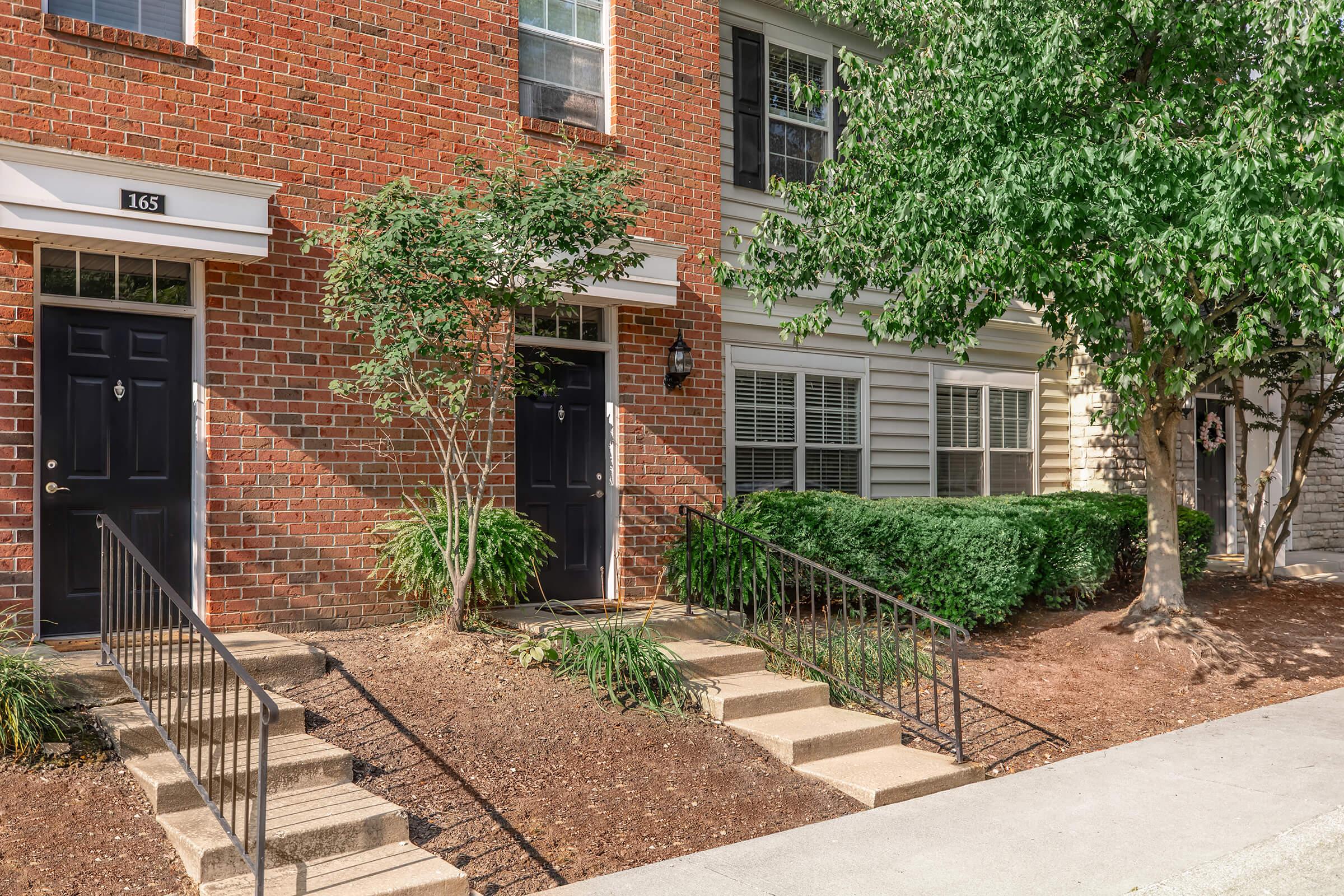 a house with bushes in front of a brick building