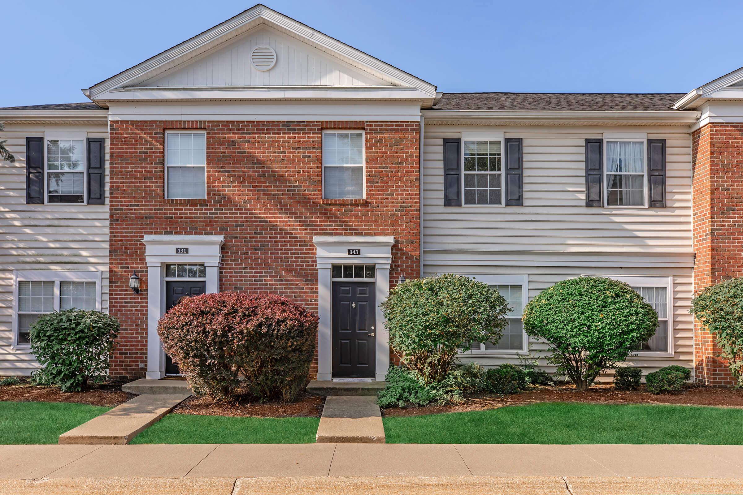 a house with a lawn in front of a brick building