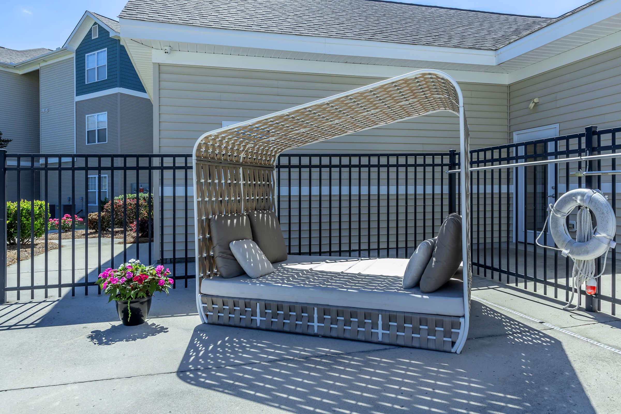 a chair sitting in front of a building with a metal fence