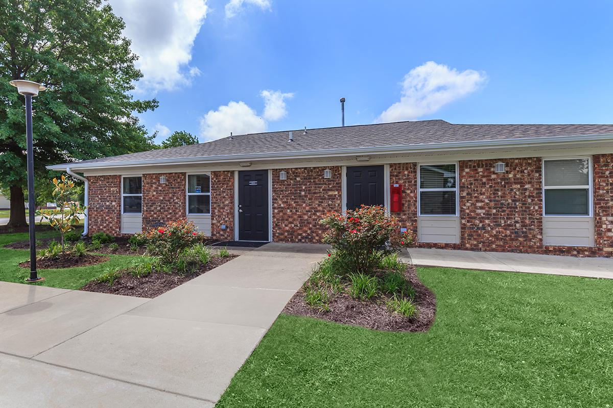 a large brick building with grass in front of a house