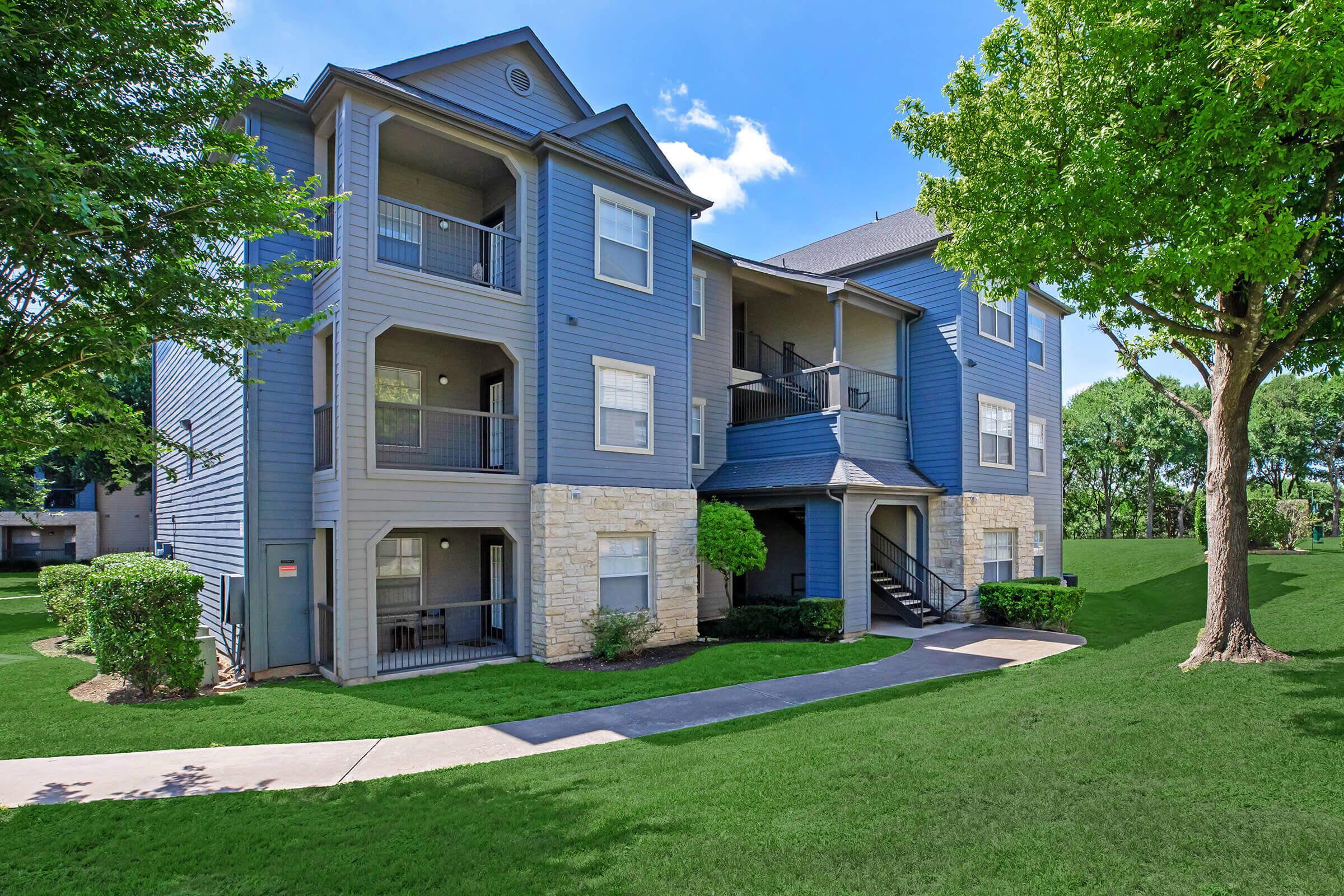 The Falls Round Rock Apartments community building with green trees