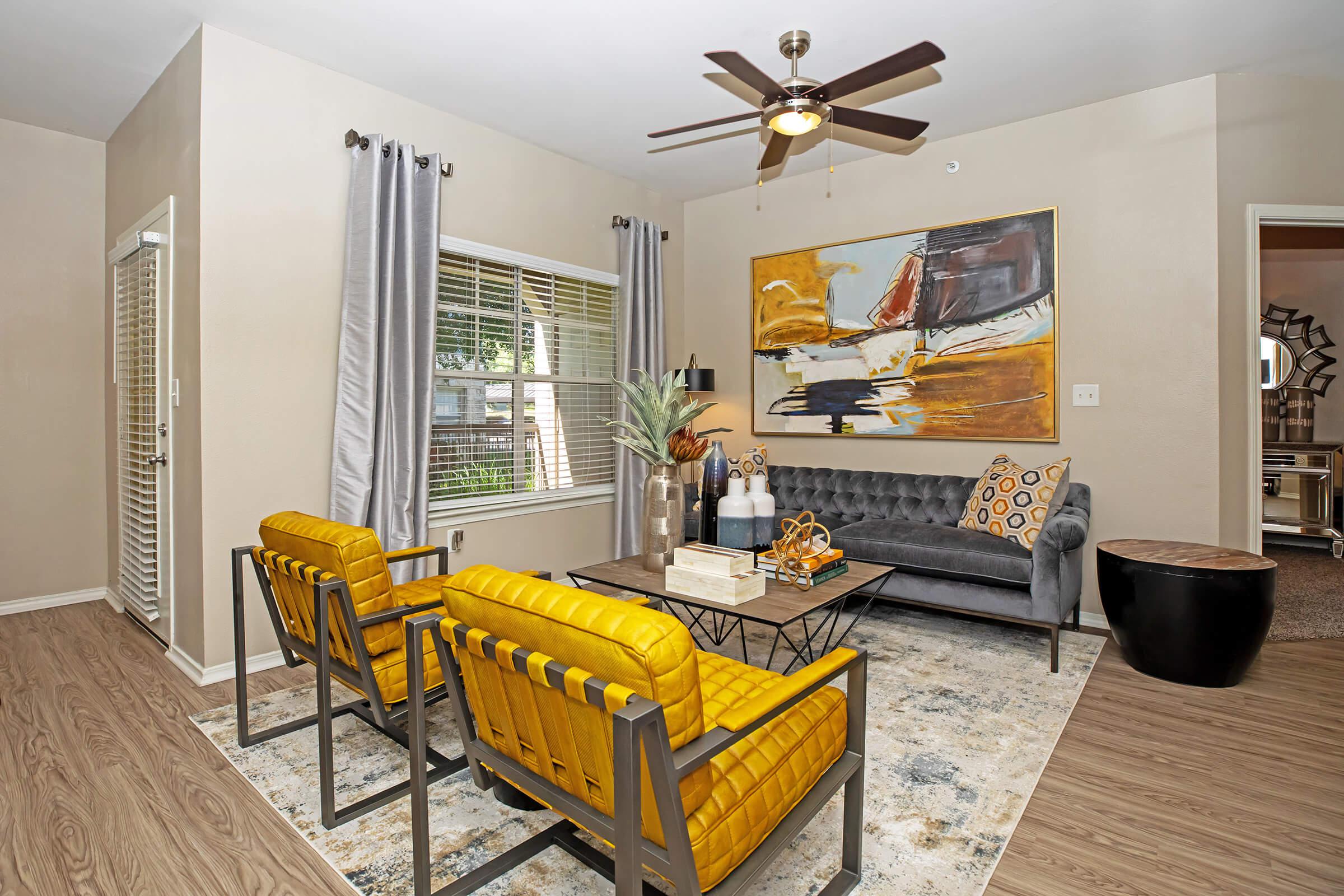 a furnished living room with yellow chairs