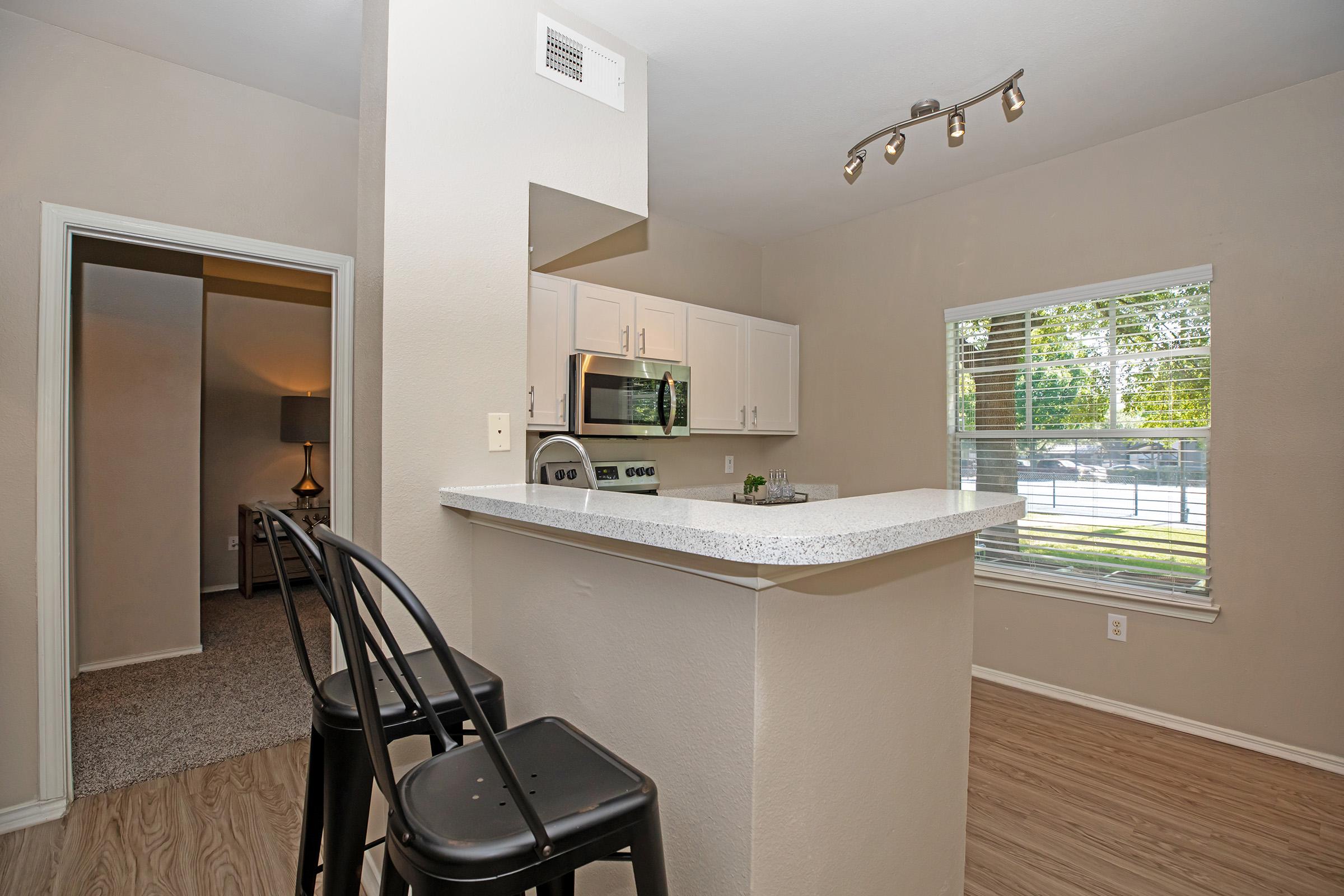 a furnished kitchen with chairs at the kitchen counter